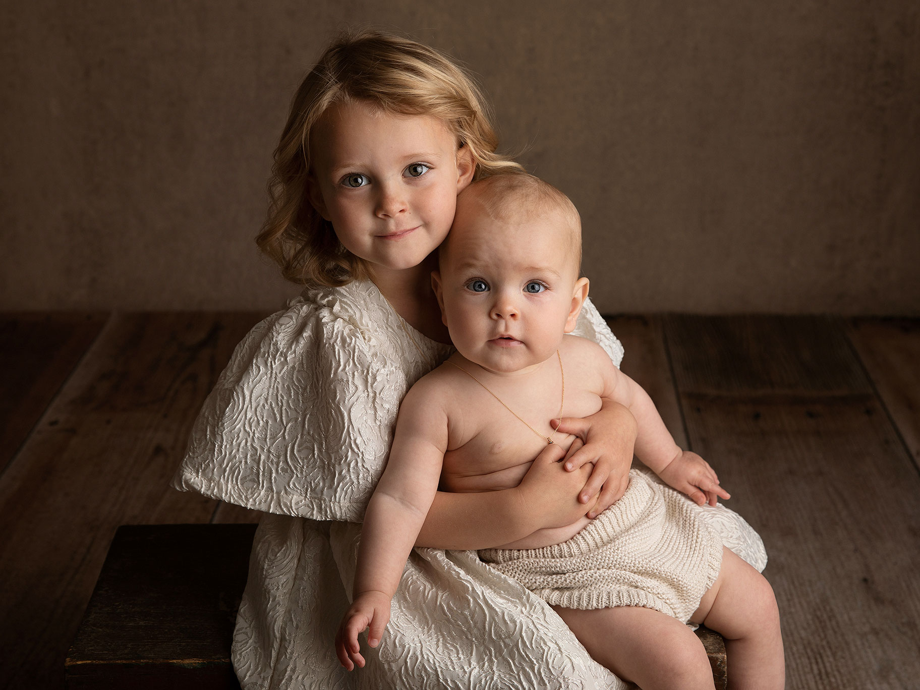 En storasyster håller om sin lillasyster under en fotografering i Malmö hos en barnfotograf.