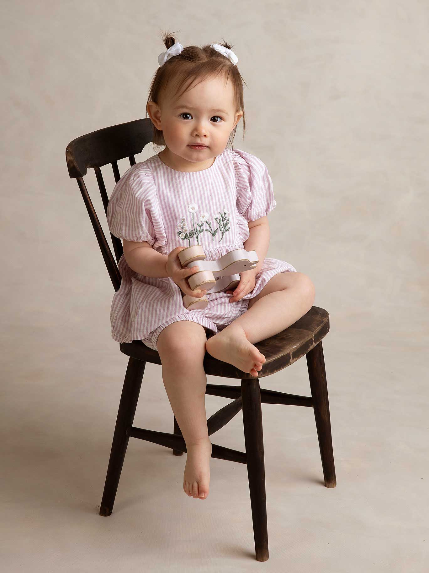 Liten flicka sitter på en stol under en barnfotografering i Malmö.