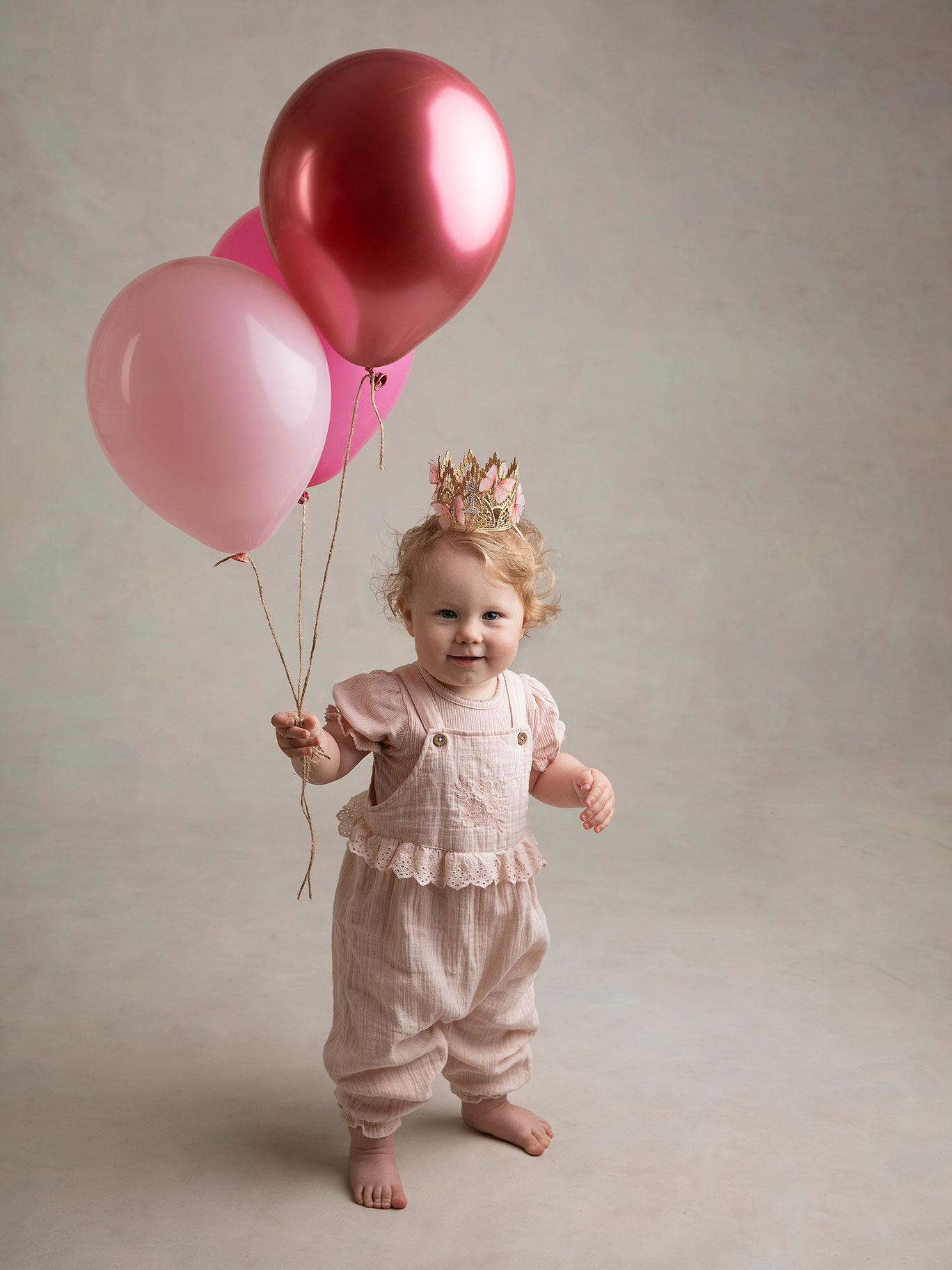 Liten flicka står upp och håller ballonger i handen under en barnfotografering i Malmö.
