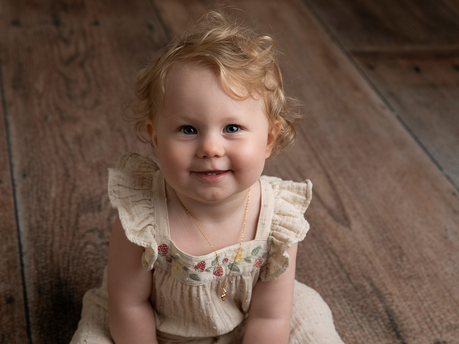 Liten flicka sitter på golvet under en barnfotografering i Malmö.