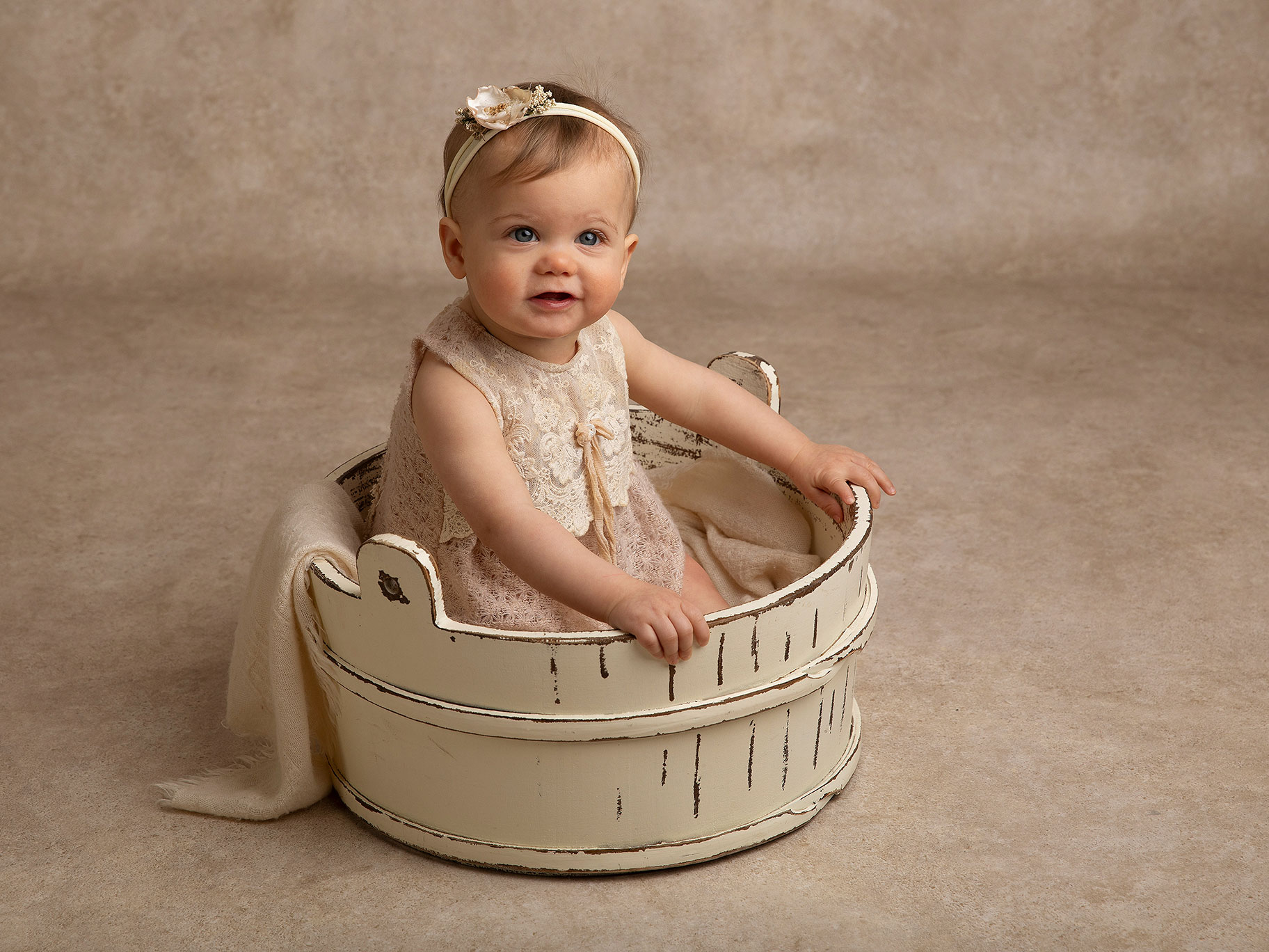 Liten flicka i en vit korg under en fotografering.