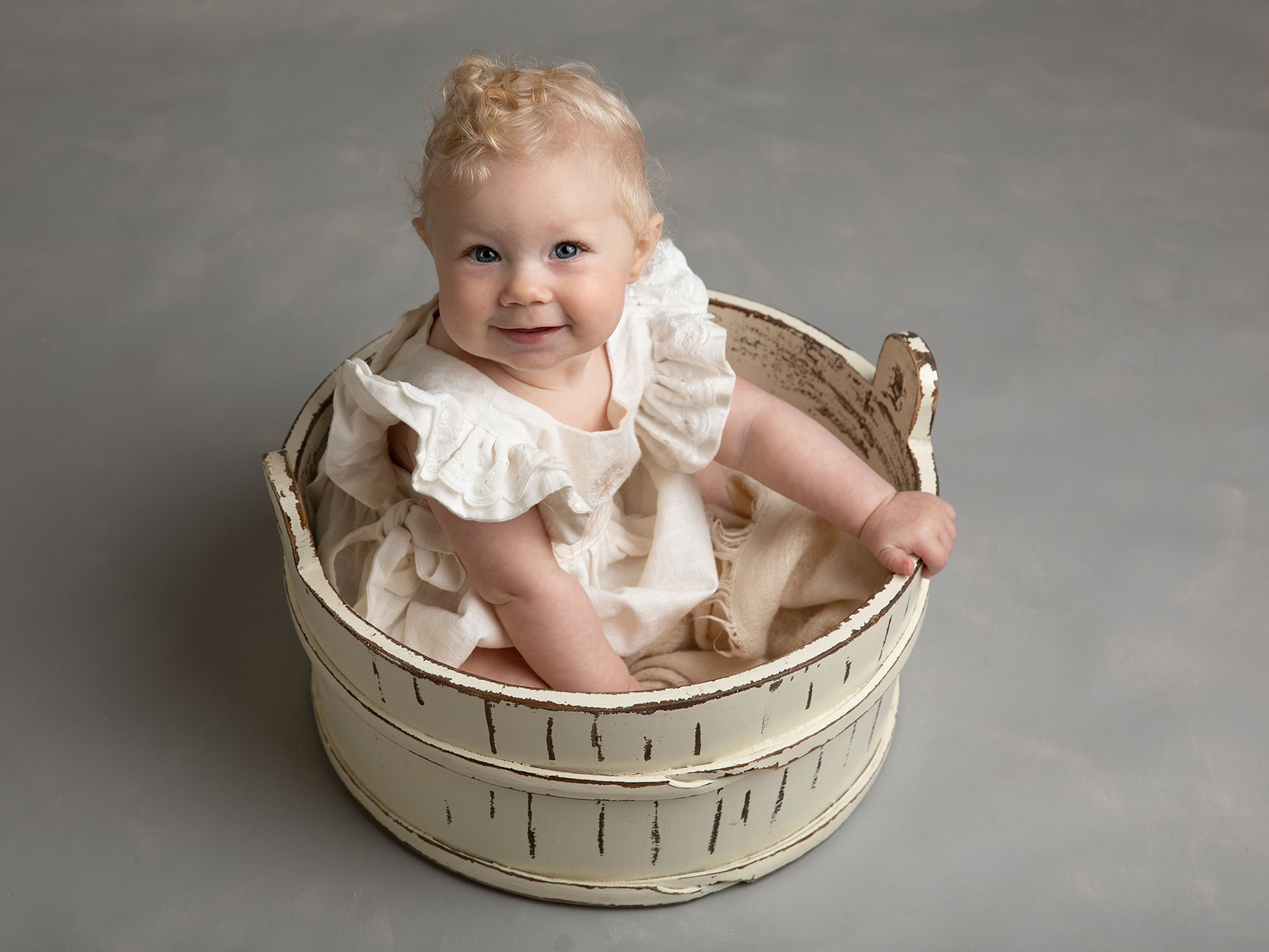 Liten och busig baby i en hink blir fotograferad i en studio i Malmö.