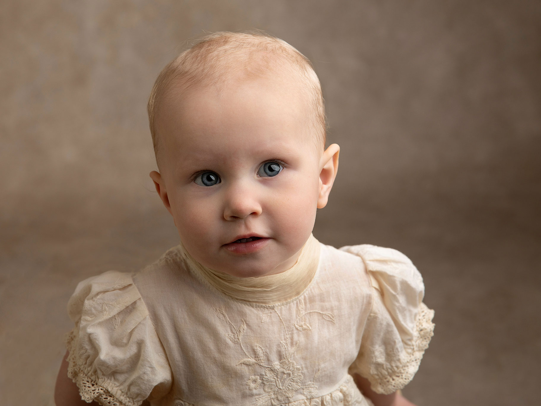 Liten flicka tittar med sina stora blåa ögon under en fotosession i Malmö.