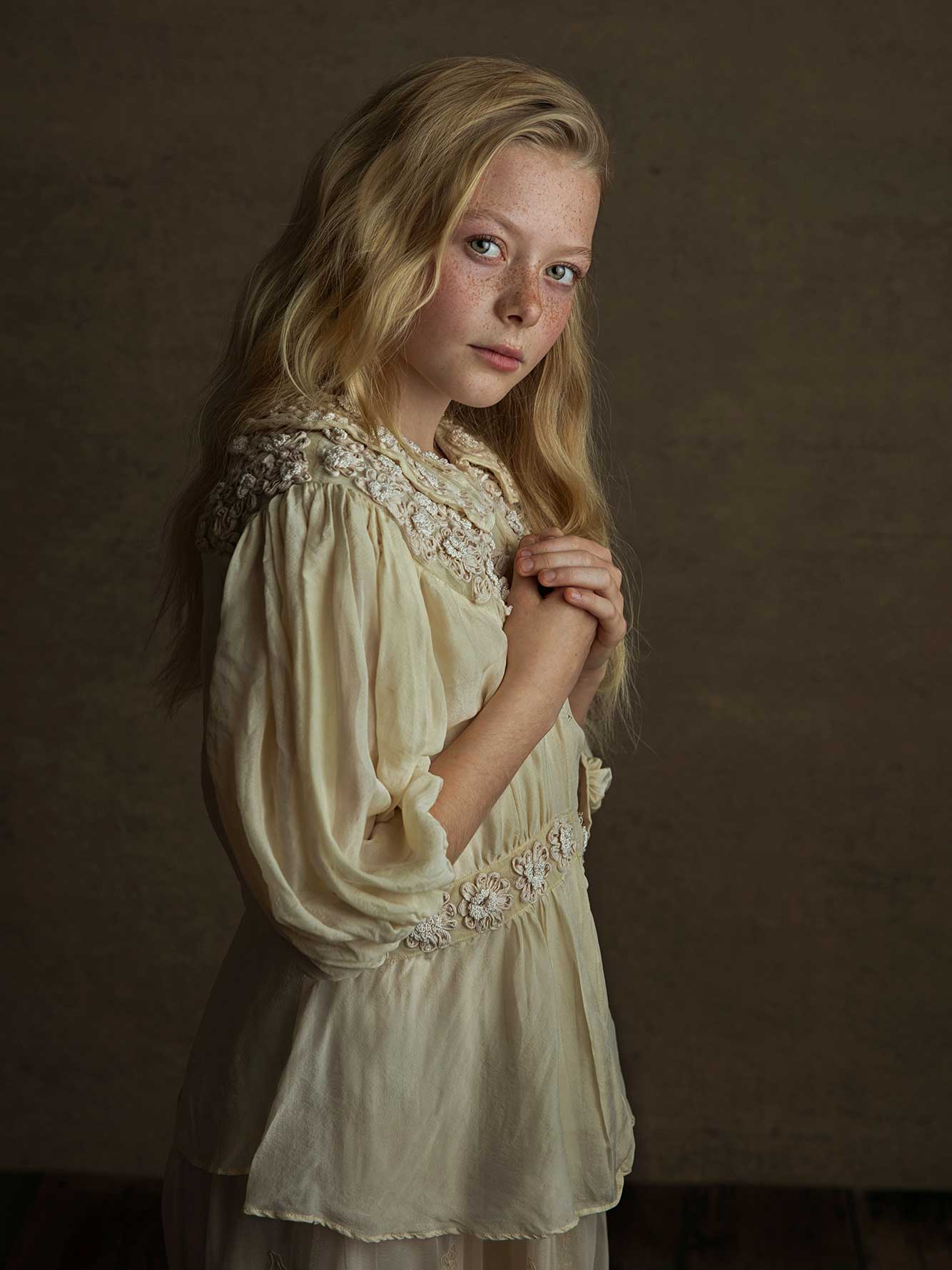 Barn i vintageinspirerad klädsel framför mörk bakgrund, fotograferat av Anna Arvidsson.