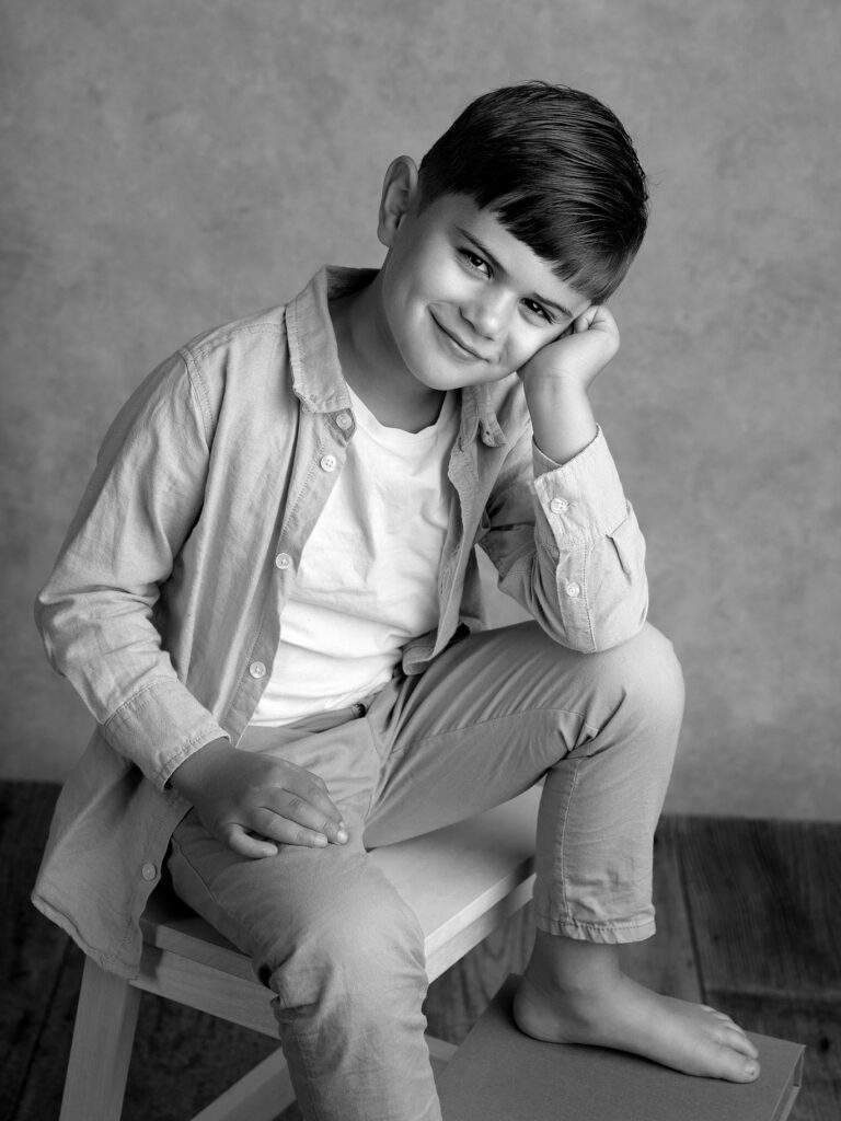 Pojke sitter och ler mot kameran hos Fotograf Anna Arvidsson i studion i Malmö.