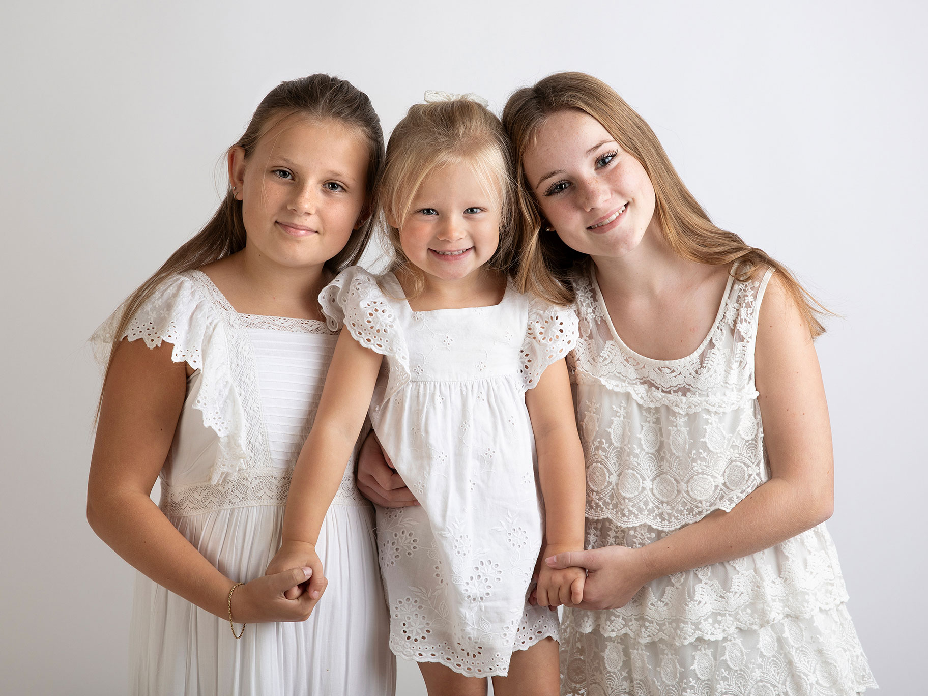 Tre syskon tittar fint mot kameran, fotograferat i Malmö.