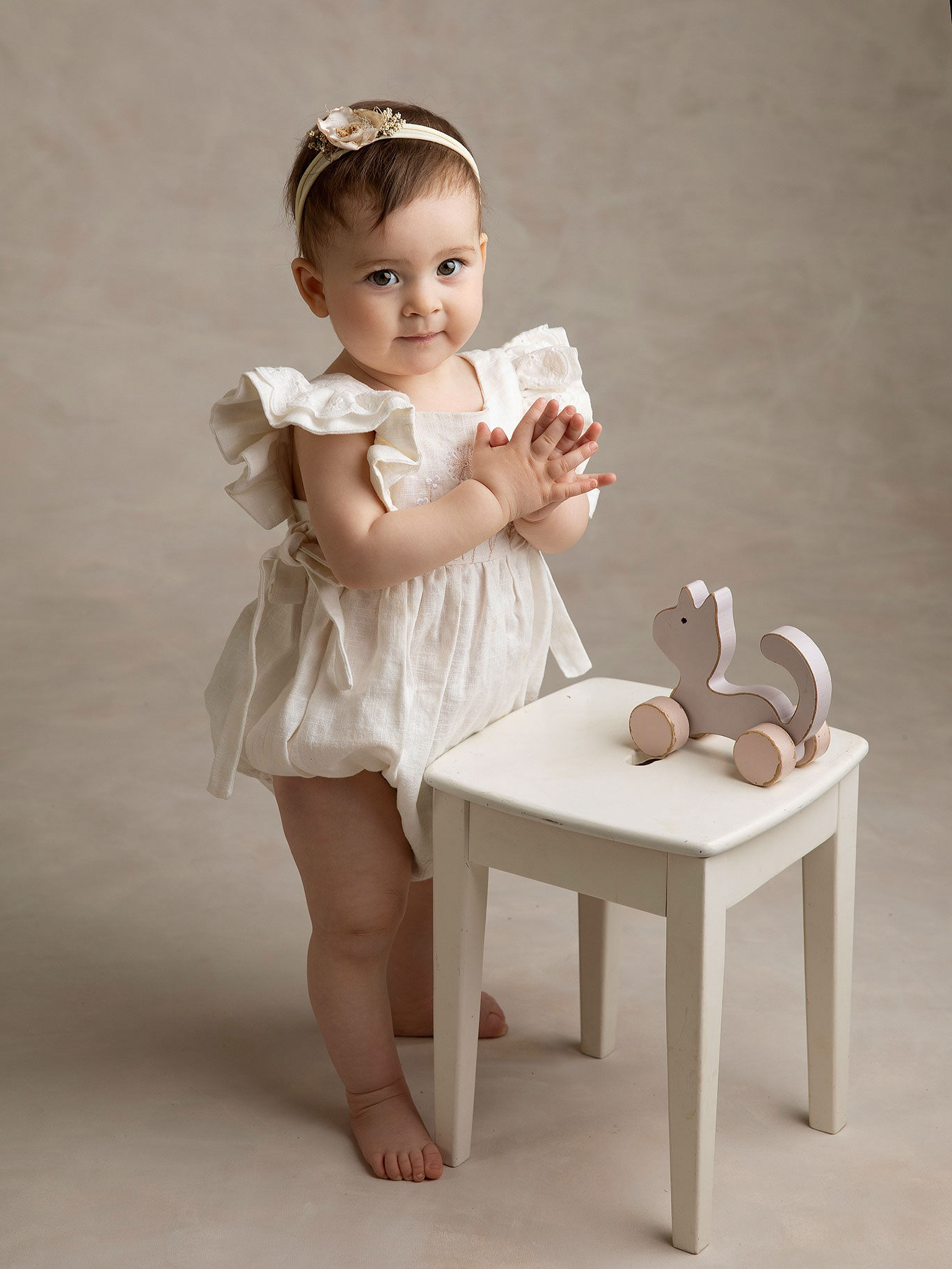 Baby tittar in i kameran och klappar händerna hos Fotograf Anna Arvidsson i studion i Malmö.