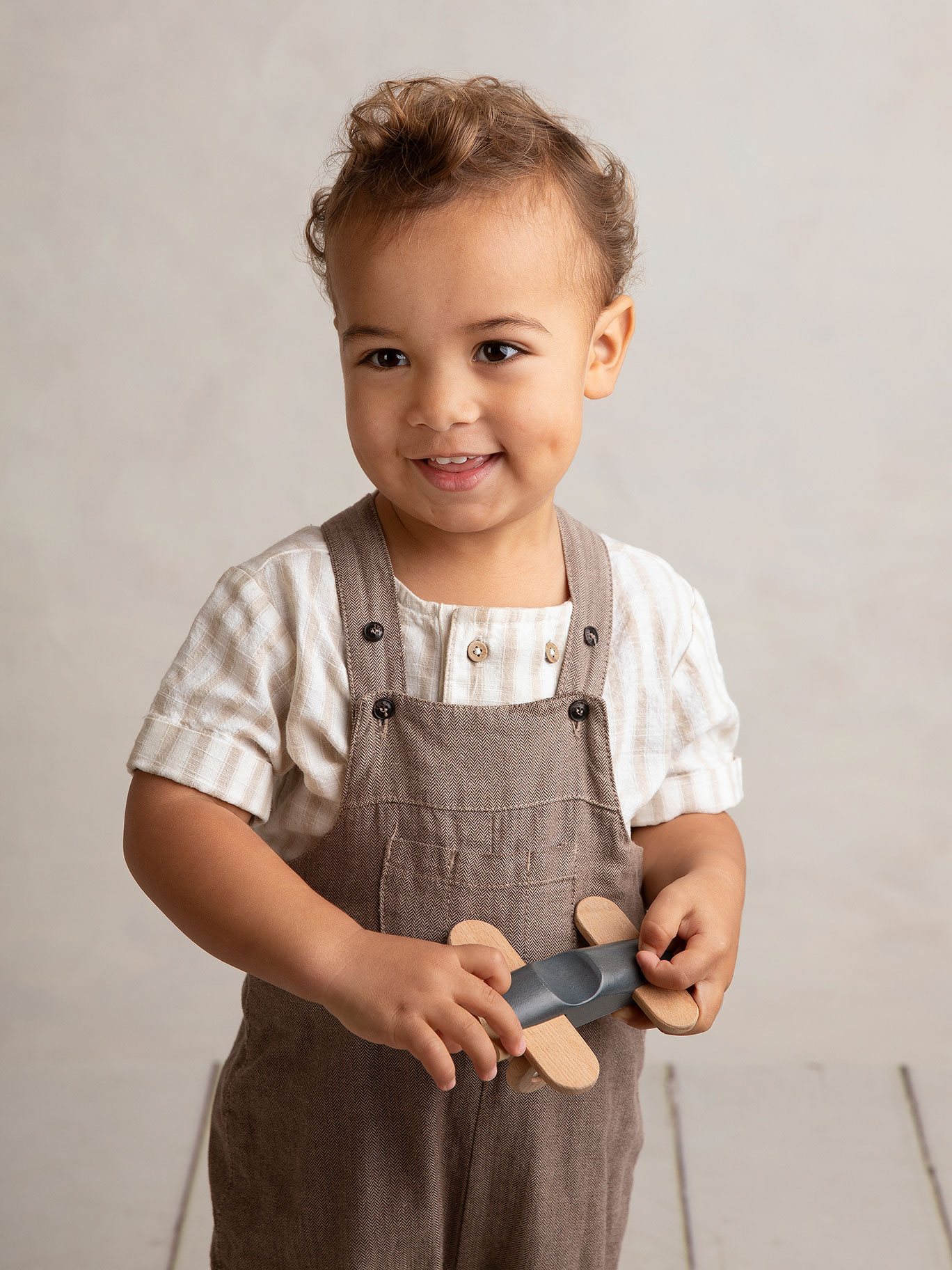 Pojke ler och håller i en leksak när han blir fotograferad i en fotostudio i Malmö.