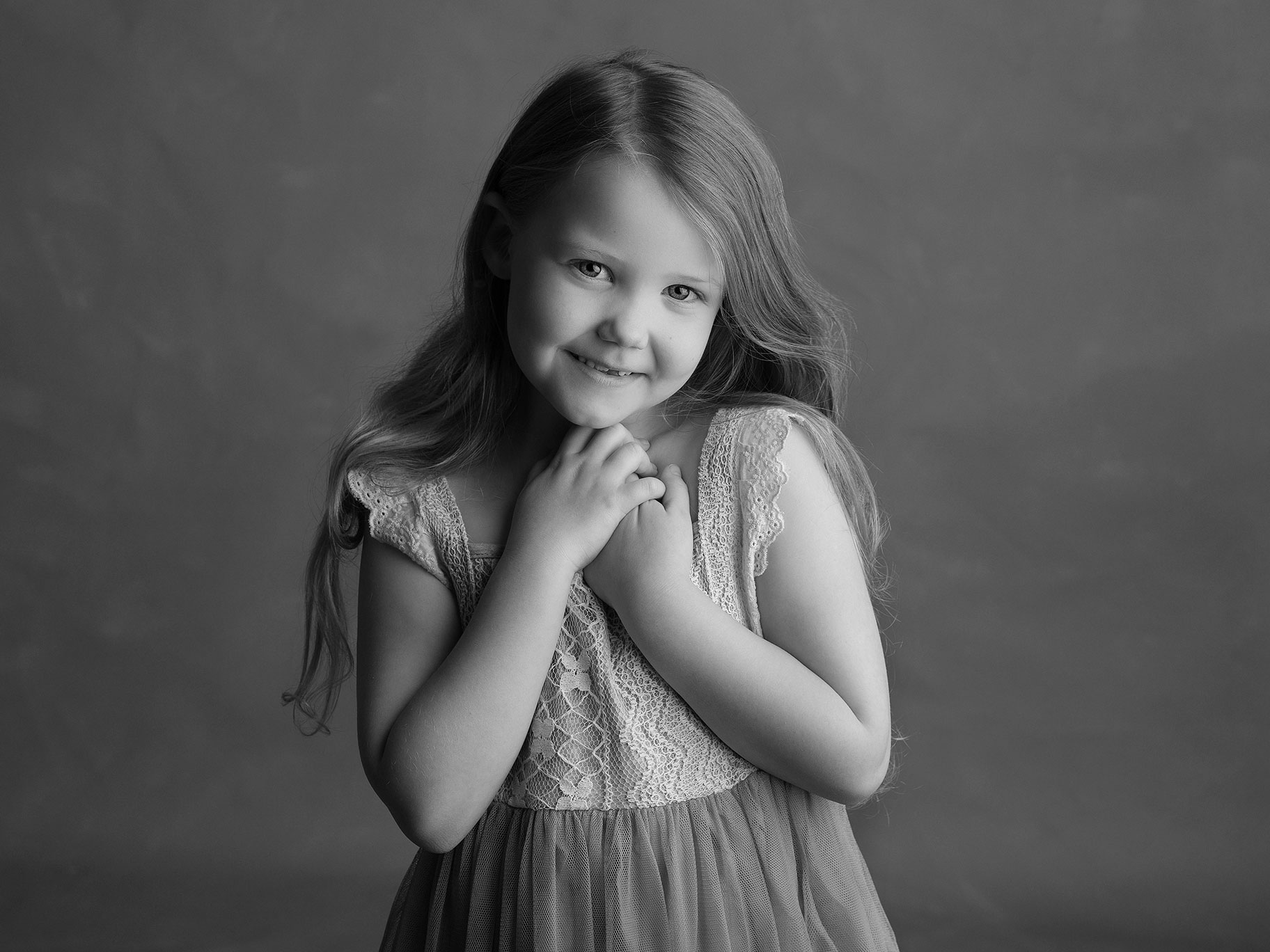 Svartvit bild på flicka i 7-årsåldern som verkar tycka om att bli fotograferad av Anna Arvidsson, familjefotograf i Malmö, Skåne.