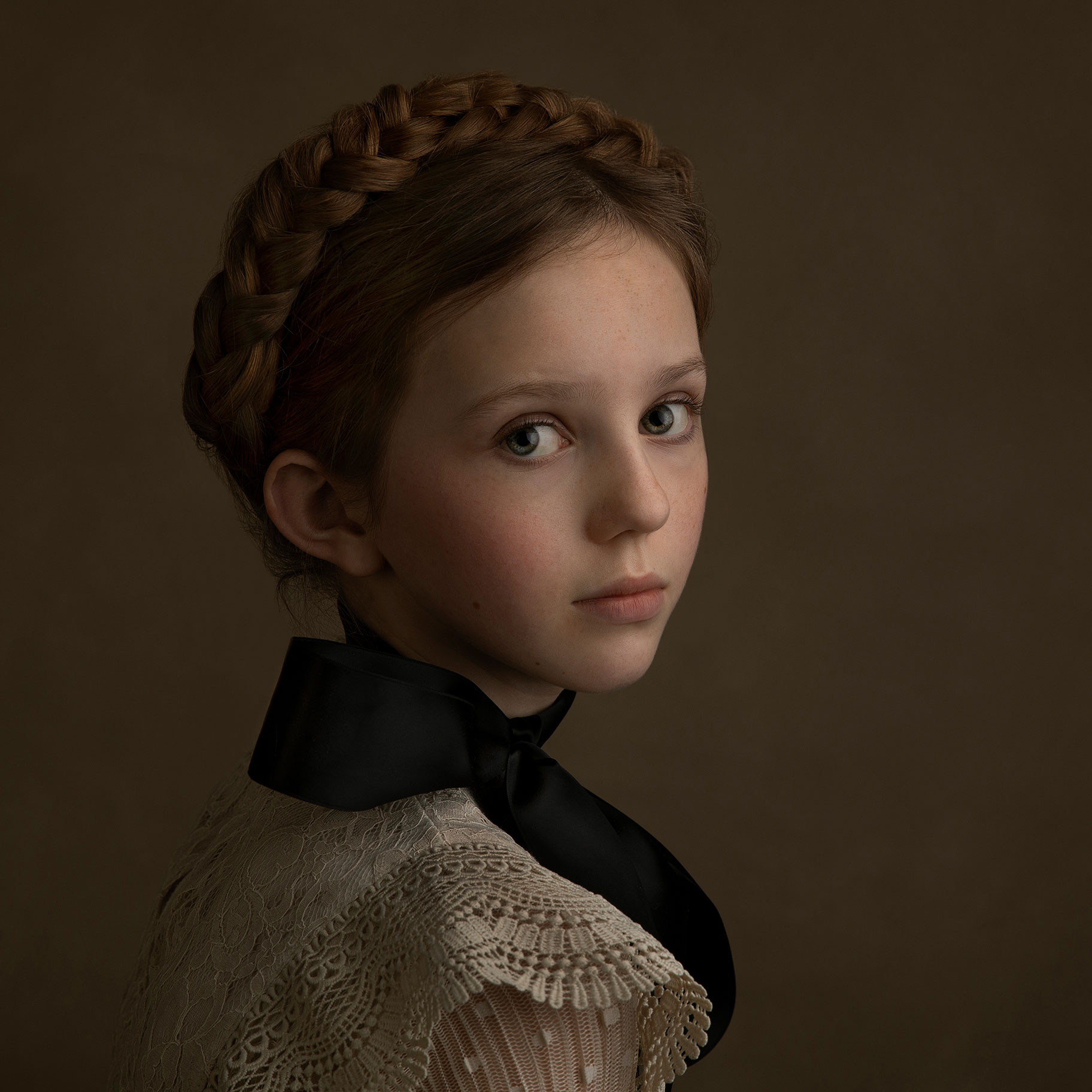 Vacker närbild på en flicka med fläta i håret och vacker spetsblus med svart rosett, tagen i studio i Malmö.