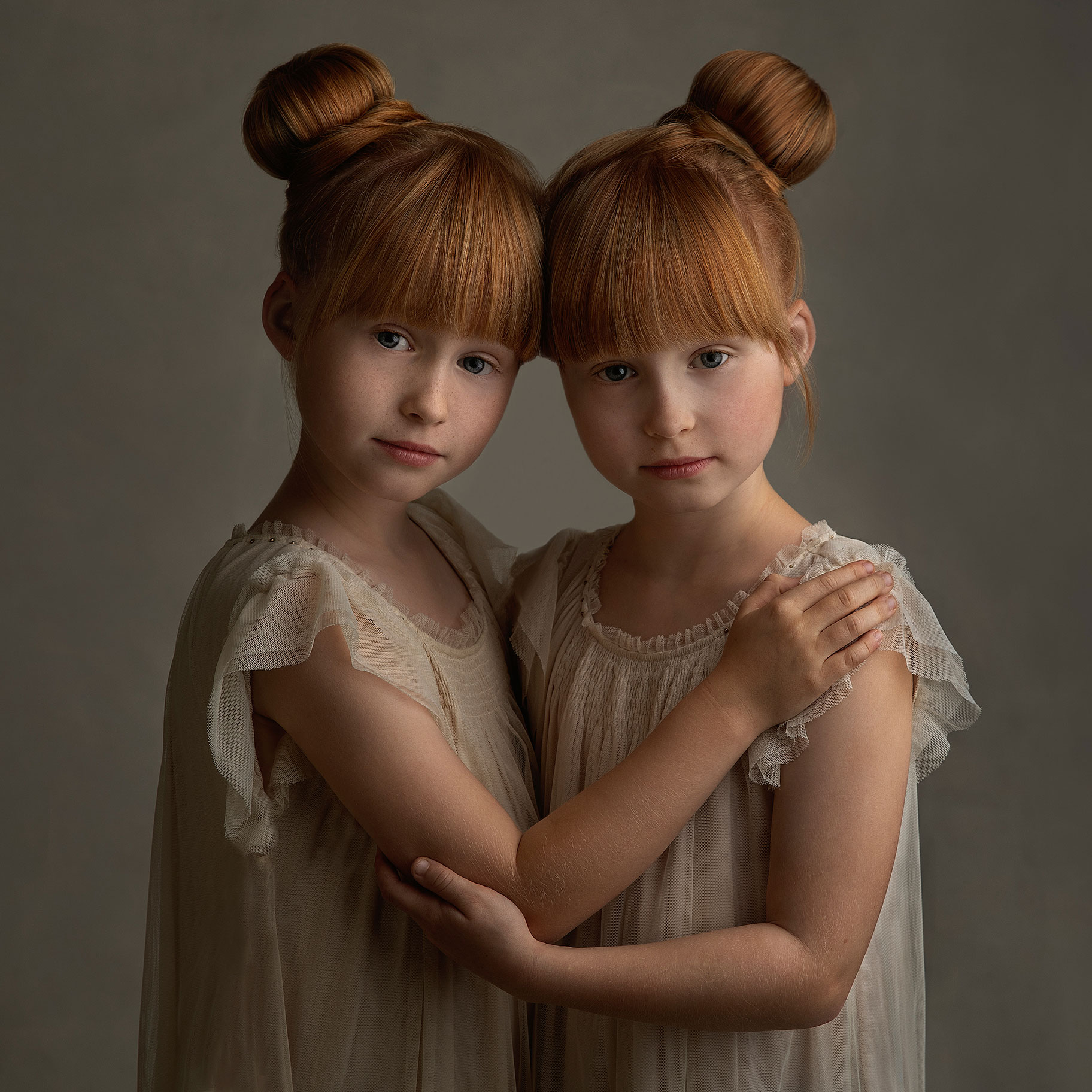 Rödhåriga tvillingflickor i underbart porträtt som fångar deras vackra blickar.