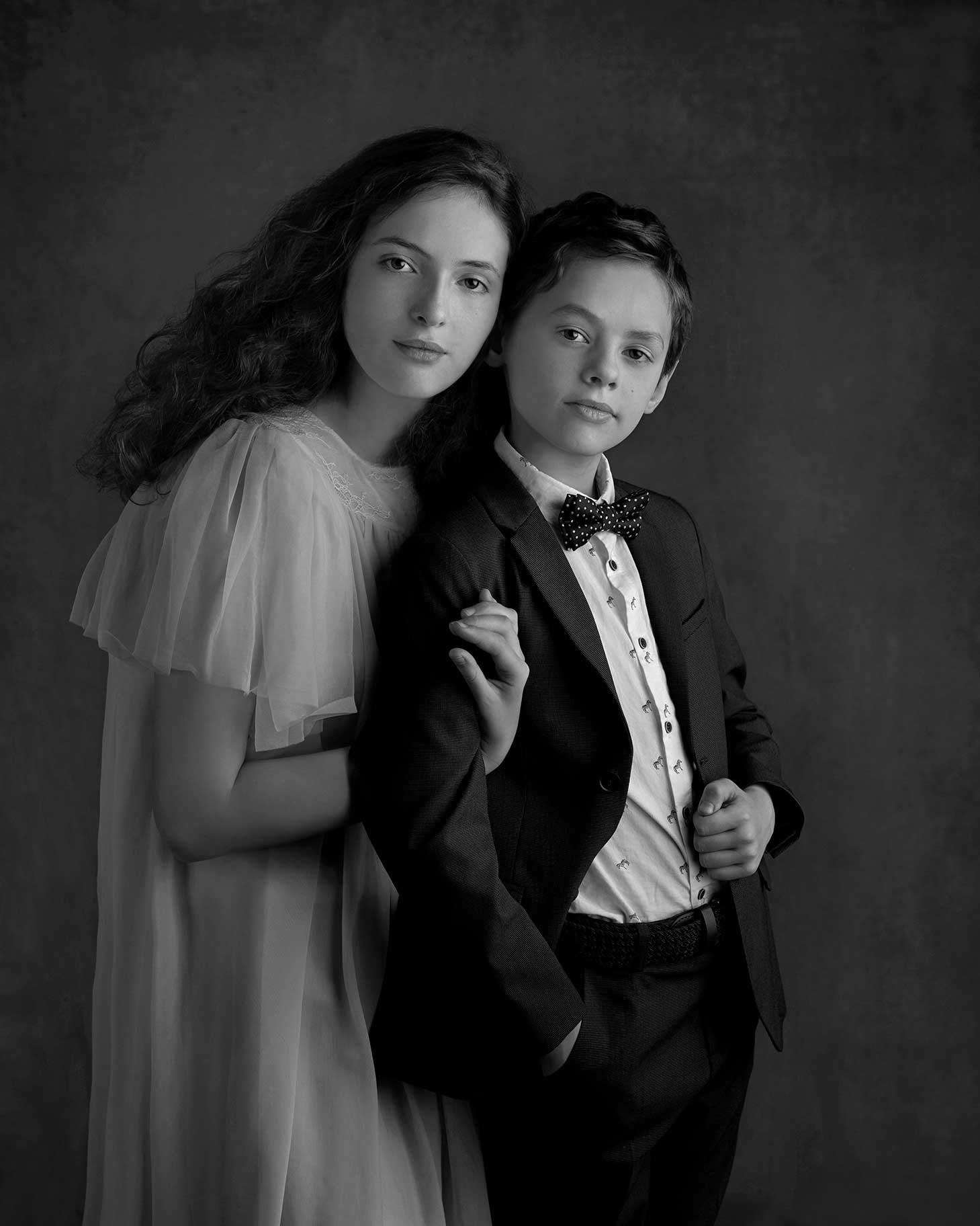 Syskon tittar fint in i kameran i fina kläder i studio i Malmö.