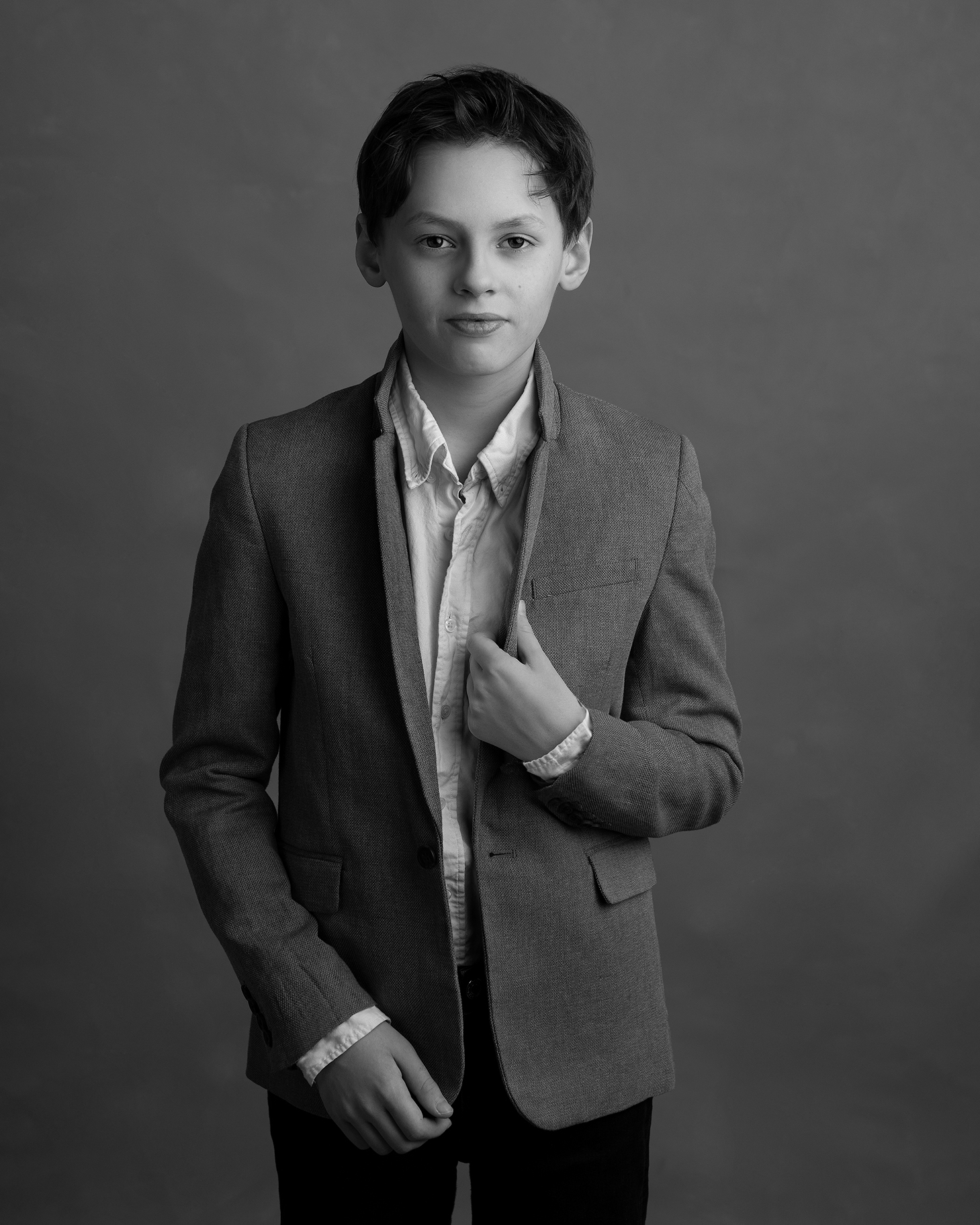 Pojke i kostym poserar framför kameran i Malmö.