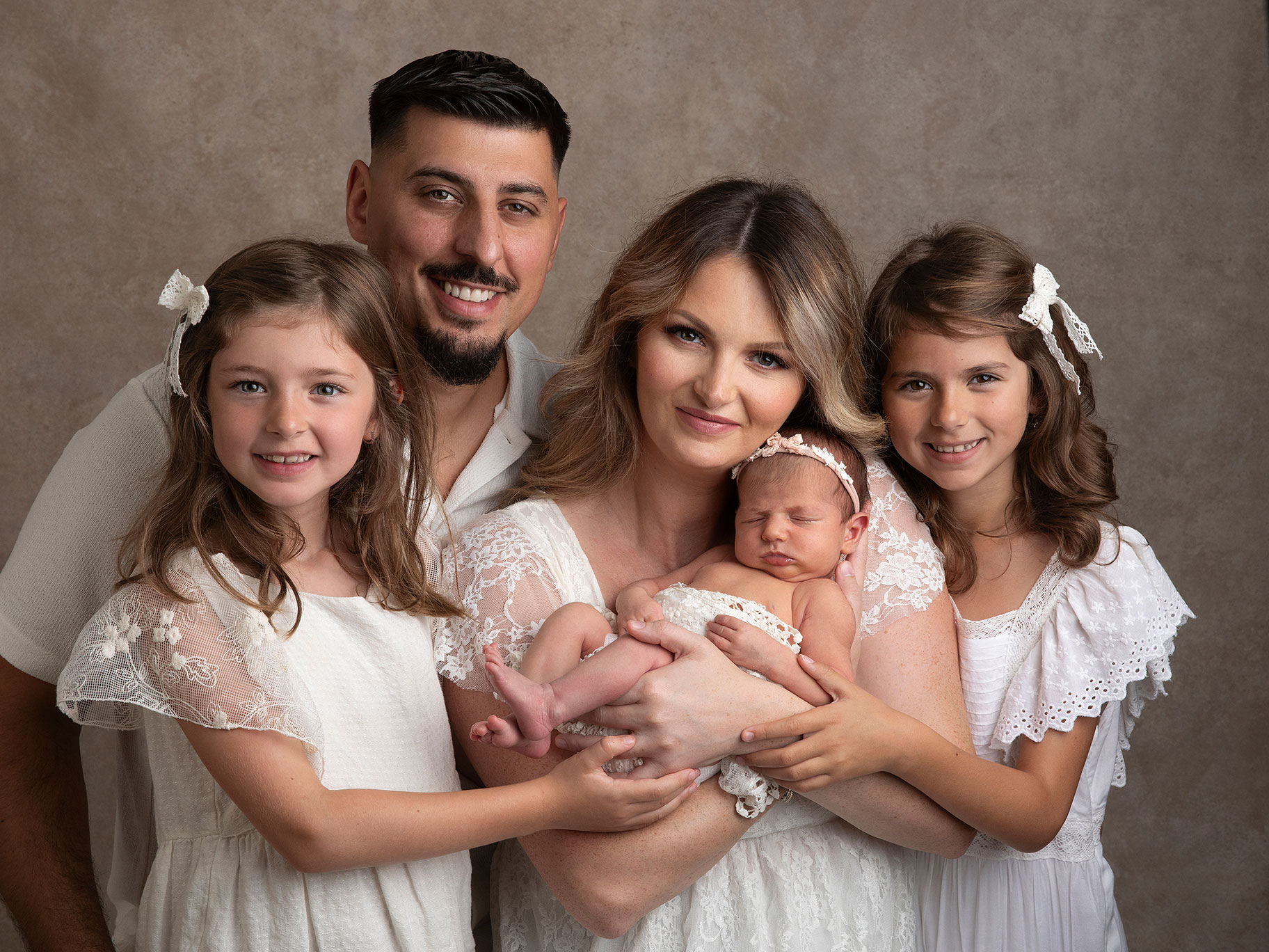 Familj fotograferad i studion i Malmö av Fotograf Anna Arvidsson när de håller sin lilla baby i famnen.