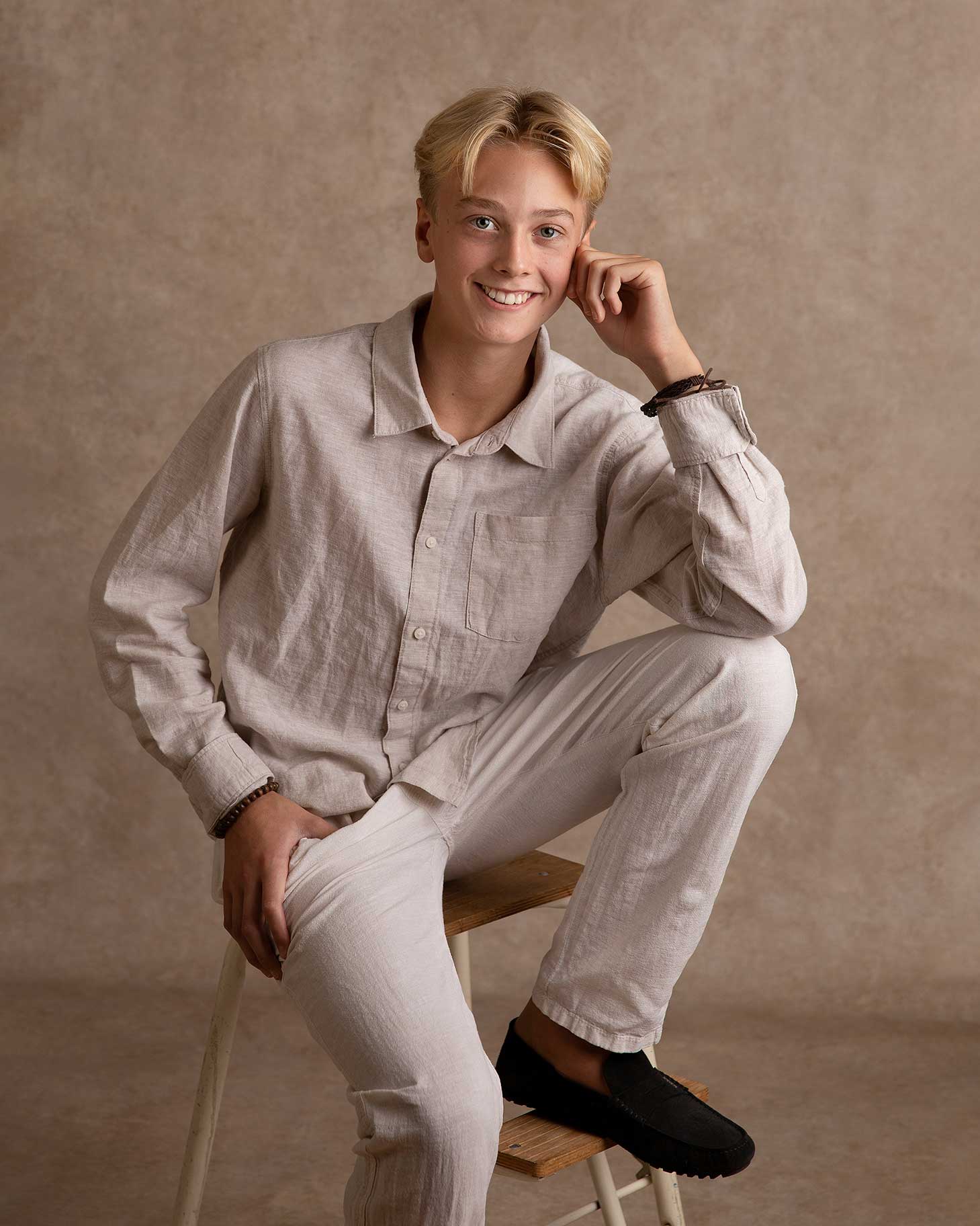 Ung kille sitter avslappnat och ler mot fotografen under en fotografering i Malmö.