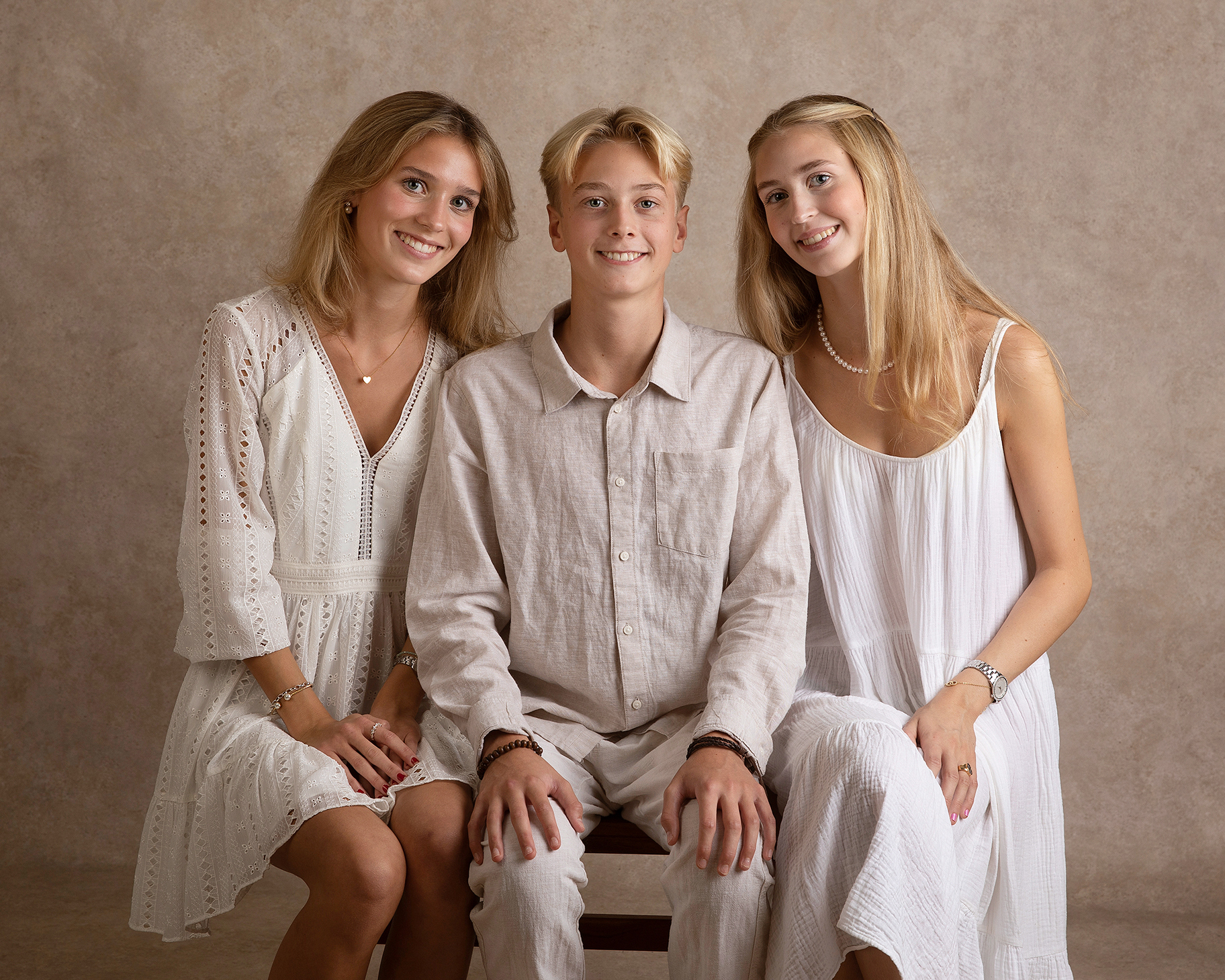 Tre syskon ler mot kameran under en familjefotografering i Malmö.