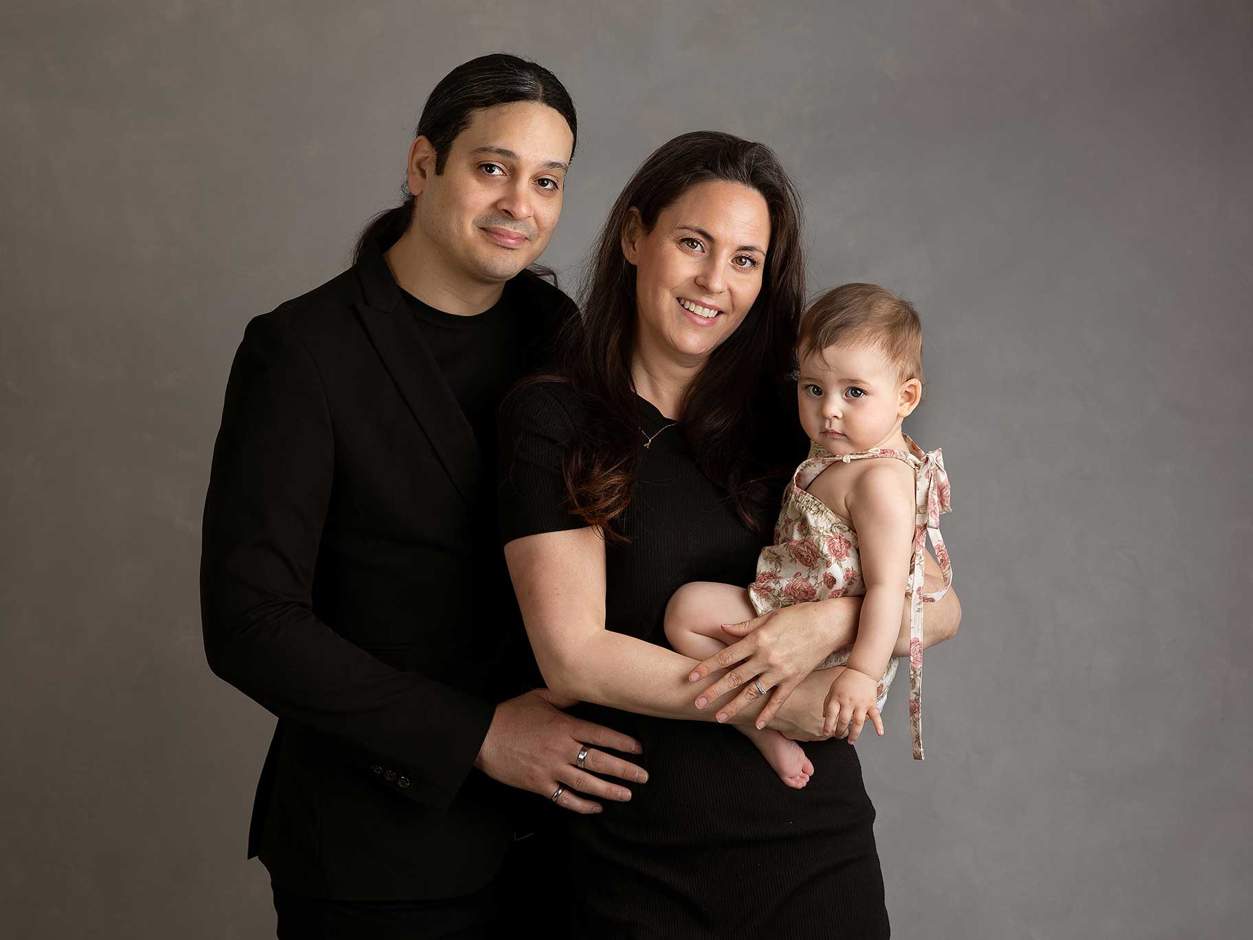 Föräldrar håller om sitt barn under en varm och personlig fotografering i Skåne.