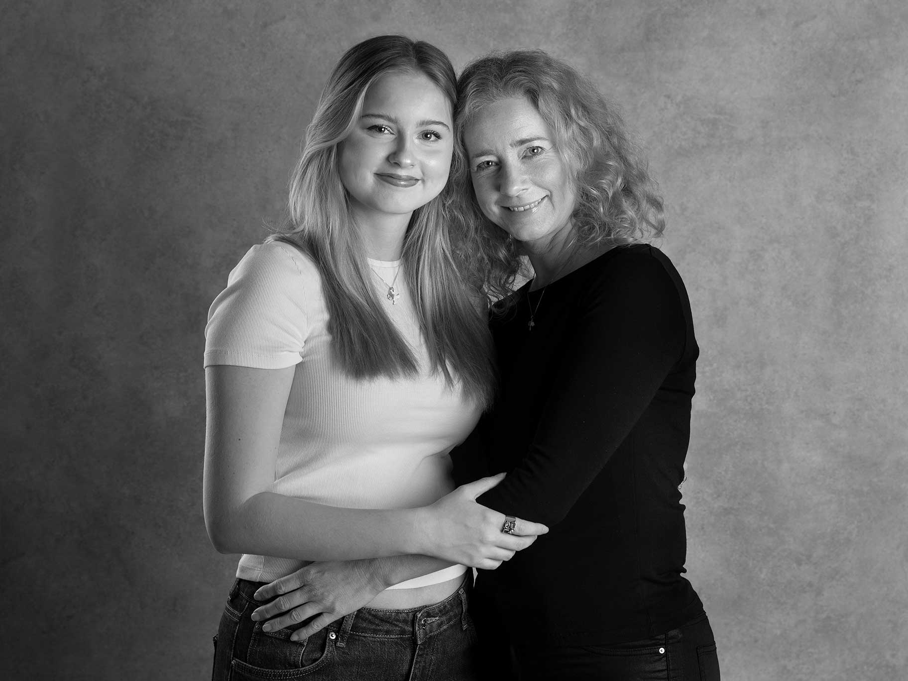 Mamma med en vuxen dotter kramar varandra under en fotografering i Malmö.