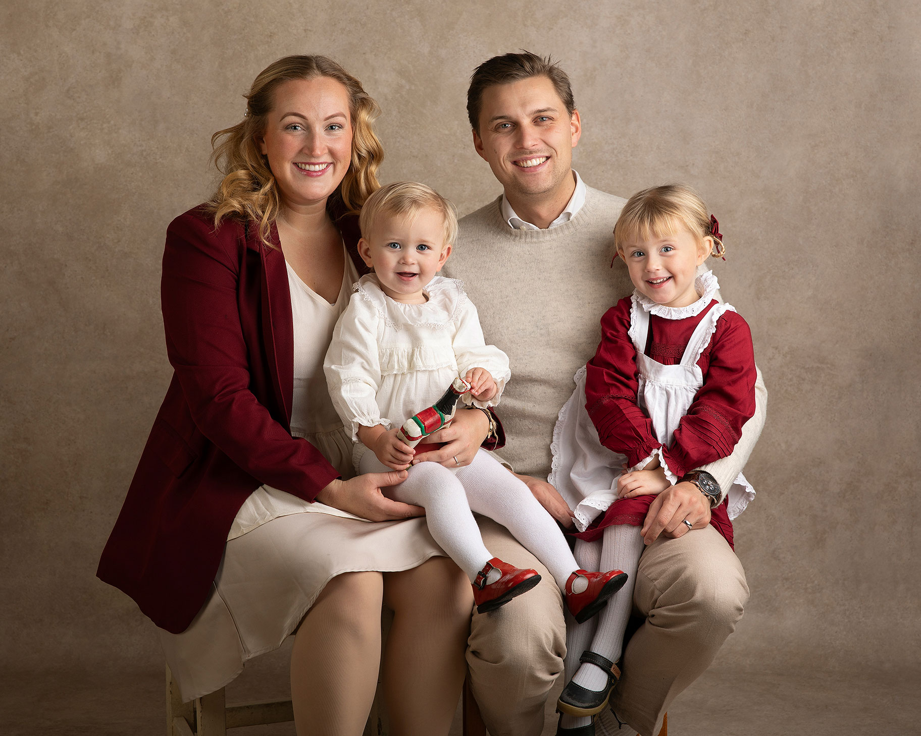 Föräldrar håller om sina barn under en varm och personlig fotografering i Skåne där de sitter tillsammans hela familjen.