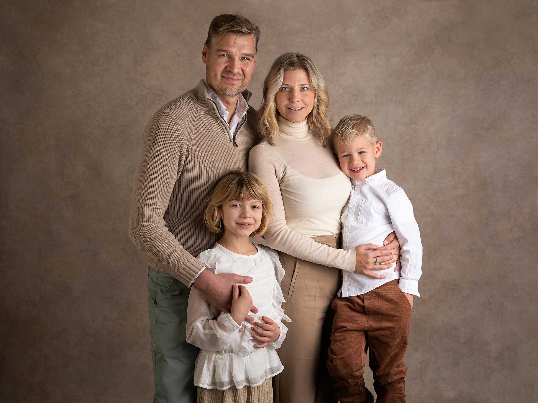 Föräldrar poserar med sina barn under en varm och personlig fotografering i Skåne.