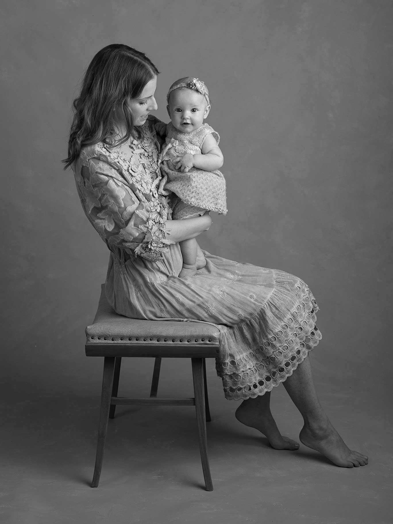 Svartvit foto där mamman tittar på sin baby som tittar med sin fina ögon mot kameran.