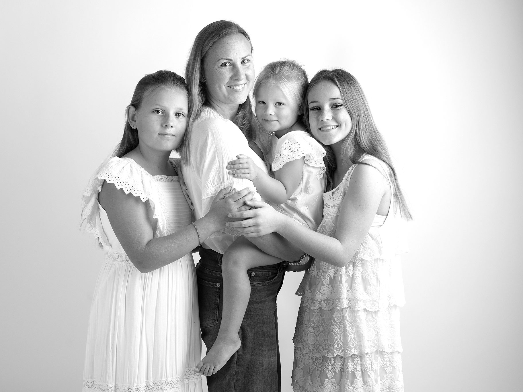En stolt mamma med sina tre döttrar blir fotograferade i en studio i Malmö.