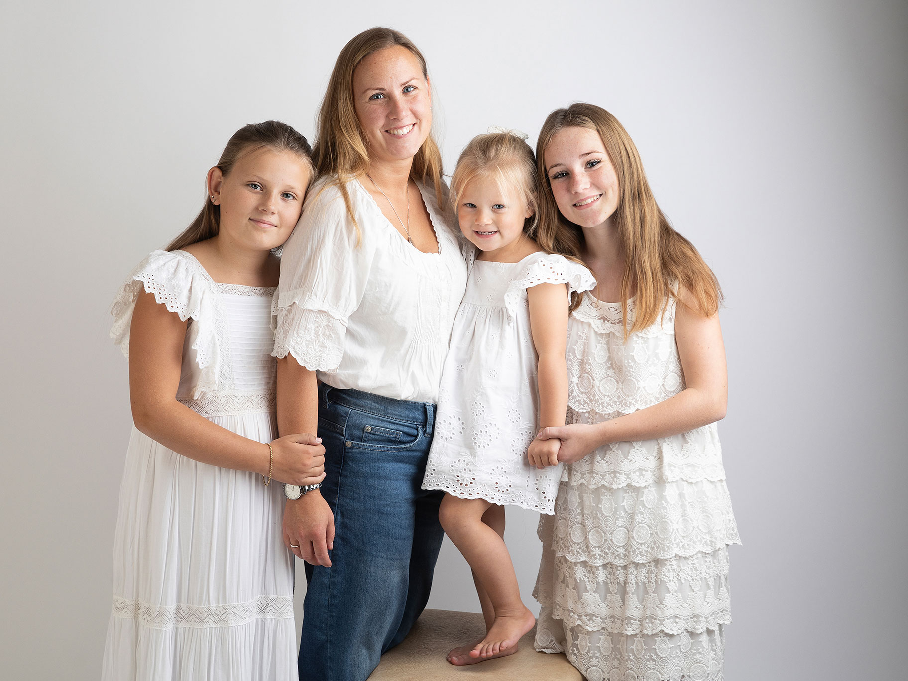 Mamma med sina tre barn ler mot fotografen i en studio i centrala Malmö.