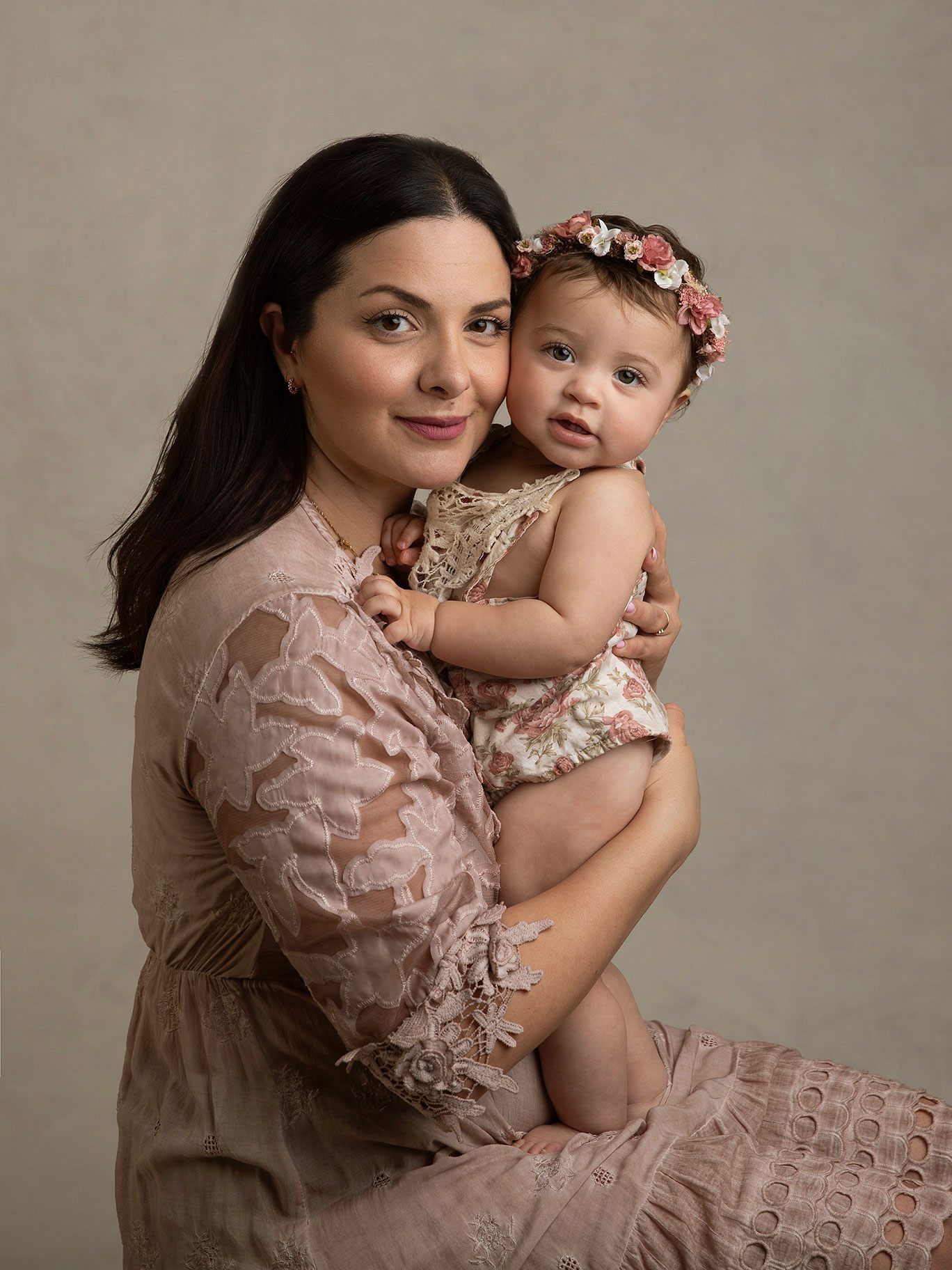 Här har fotografen fångat en vacker bild på en mamma med sin lilla babyflicka i famnen när de båda tittar fint mot kameran.
