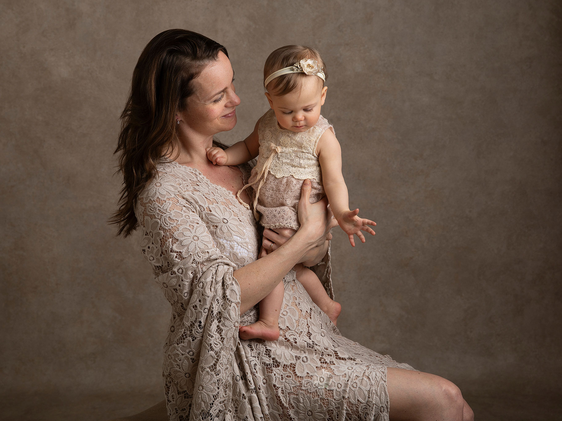 Mamma i fin klänning tittar stolt på sin baby under en fotografering av fotografen Anna Arvidsson i hennes studio i Malmö.