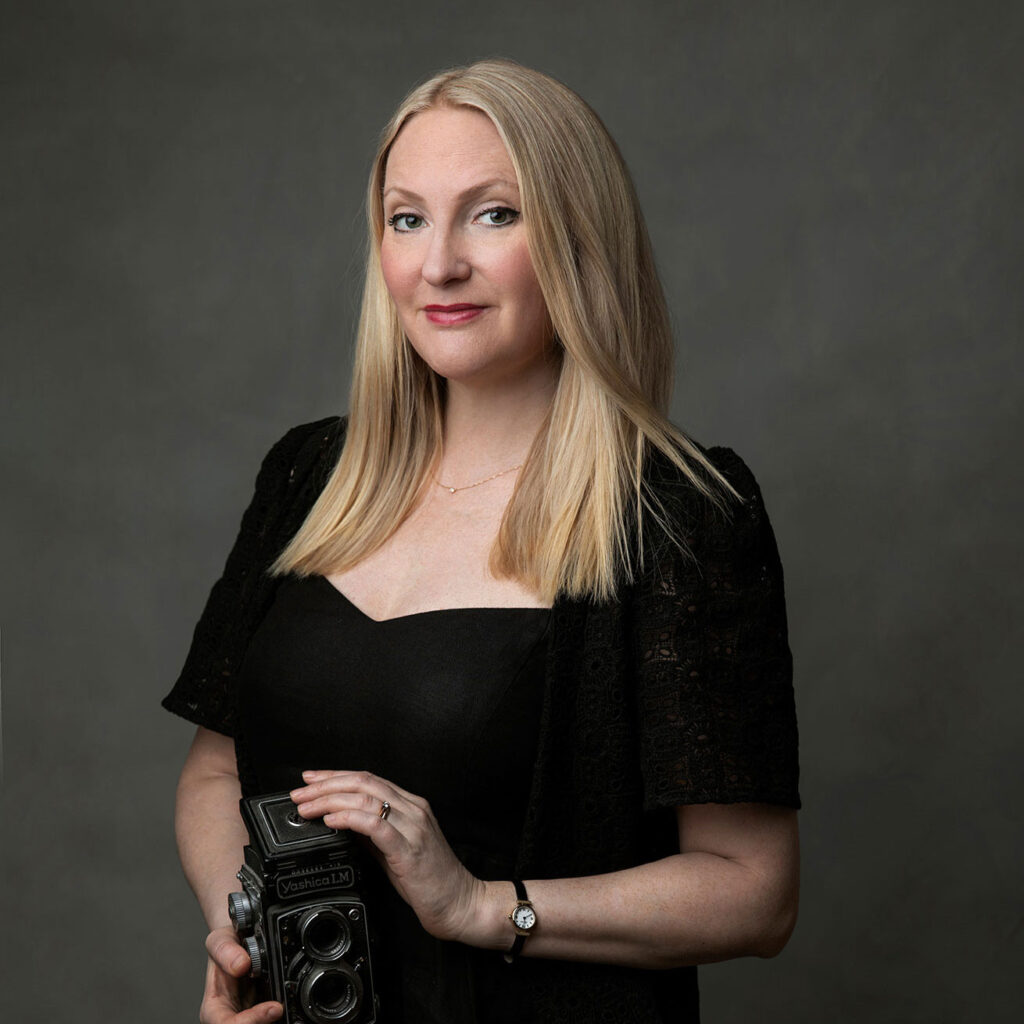 Fotografen Anna Arvidsson står och håller en kamera i handen i studion i Malmö.