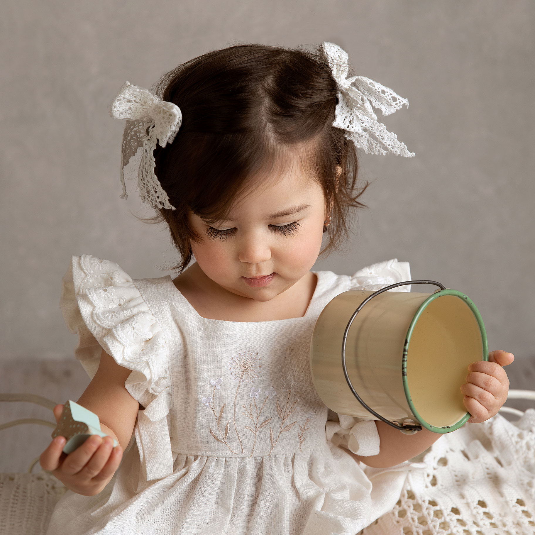 Liten baby med stora vita rosetter i håret blir fotograferad i studion hos Anna Arvidsson, fotograf i Malmö.