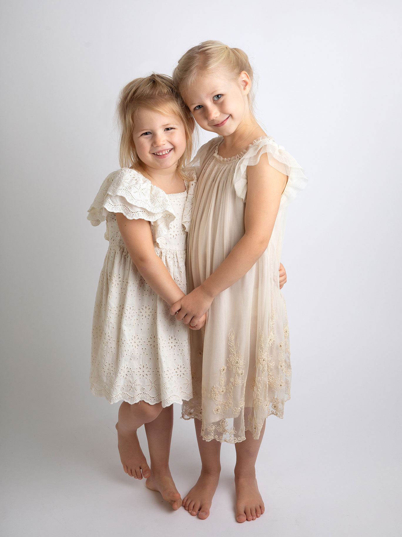 Syskon håller hand och ler mot kameran hos Fotograf Anna Arvidsson i Malmö, Skåne.