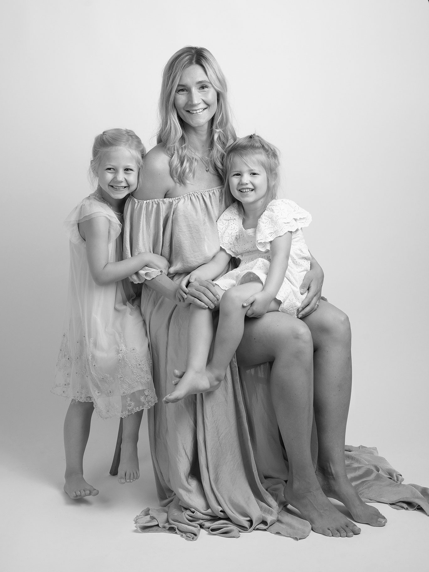 Modern och stilren bild tagen i en fotostudio i Malmö med vit bakgrund på en mamma och hennes två barn.