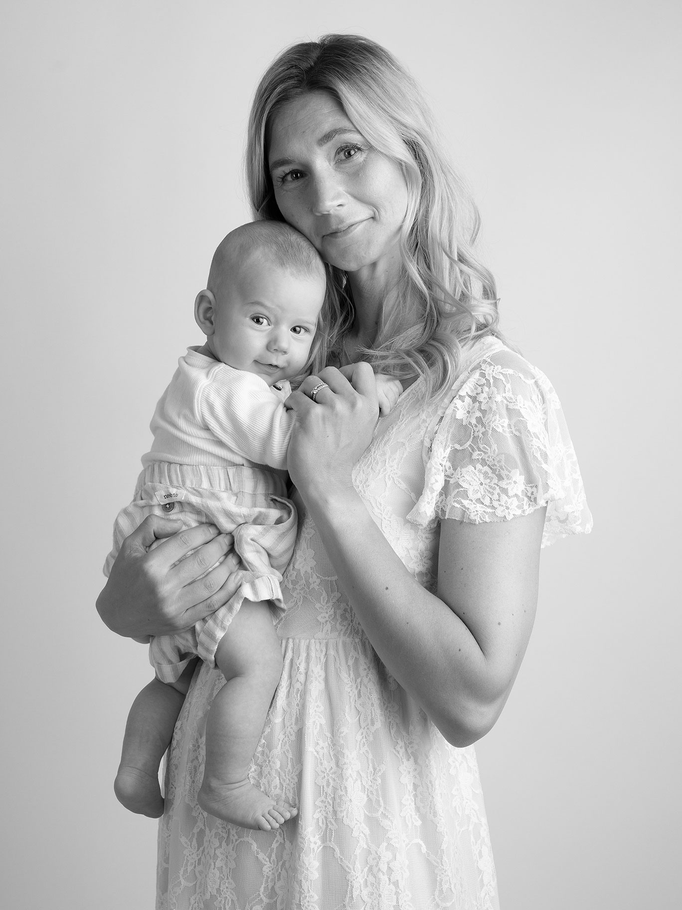 En nybliven mamma med sin lilla baby. Fotografen har fångat båda när de tittar fint in i kameran under en fotosession i Malmö.