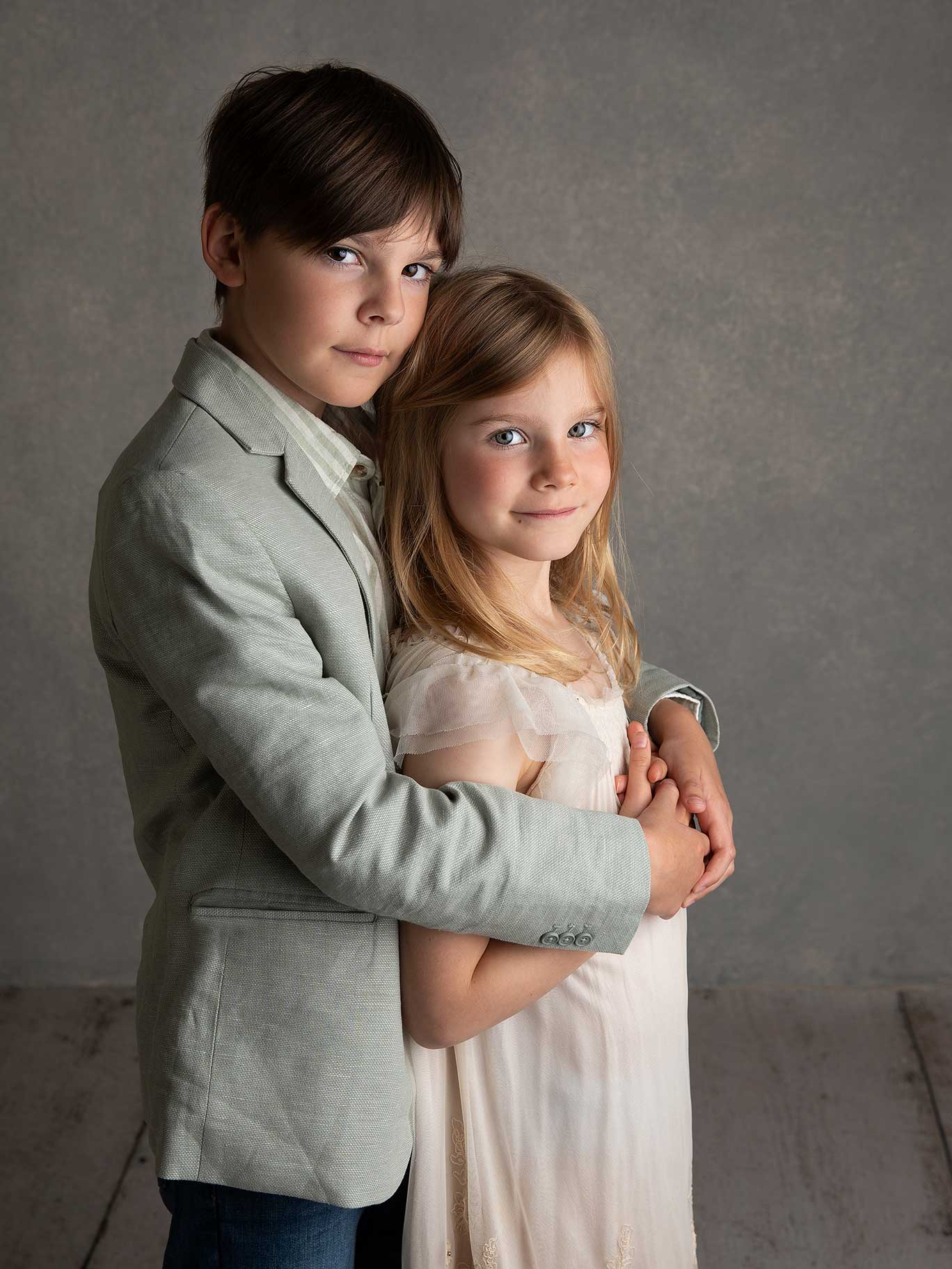 Två syskon håller om varandra och tittar rakt in i kameran, här har fotografen lyckats fånga ett fint ögonblick i studion i Malmö.