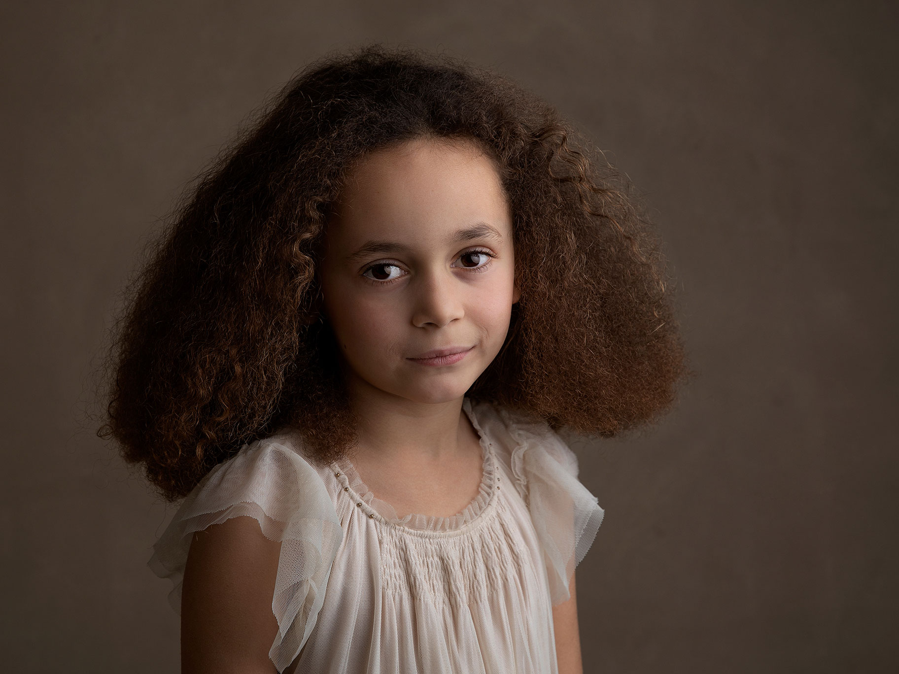 Vackert foto av flicka med fint hår som tittar mot kameran hos en familjefotograf i Malmö, Skåne.