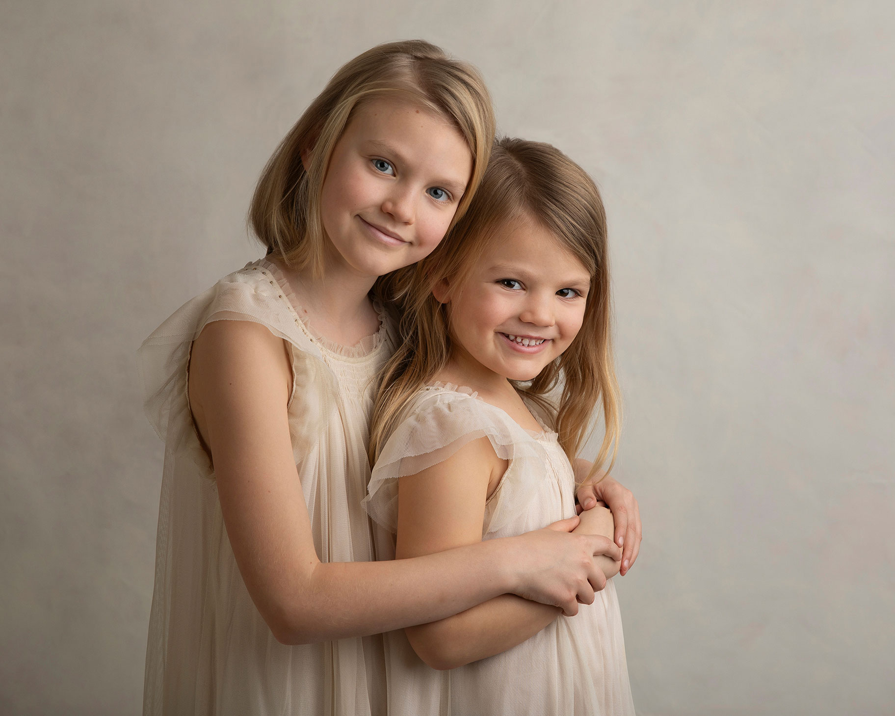 Två systrar håller om varandra under en barnfotografering i Skåne.