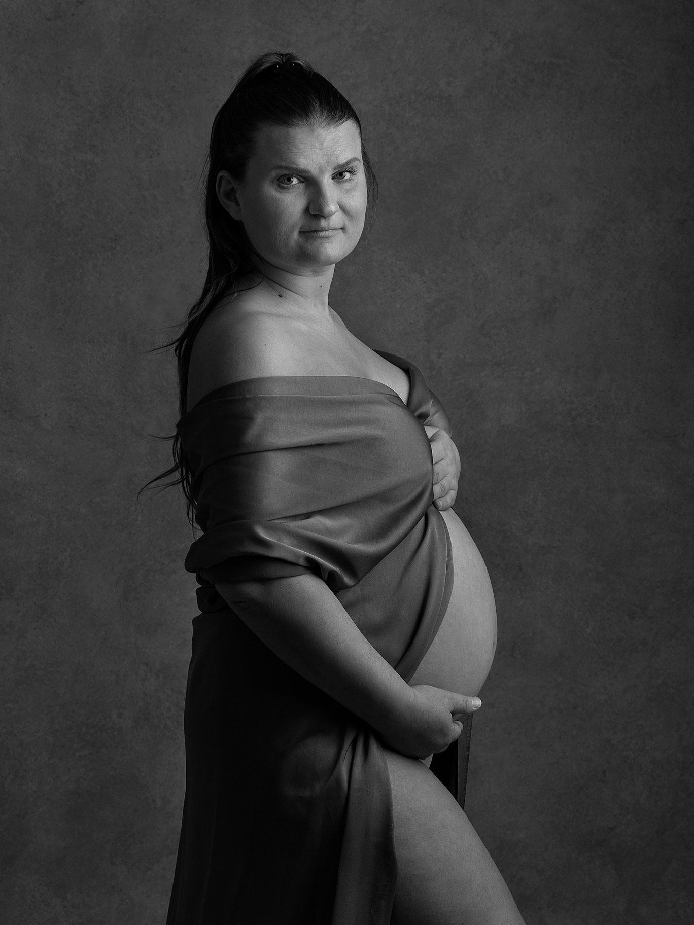 Gravidfotografering i minimalistisk stil med mörka toner, i Malmö-studio.