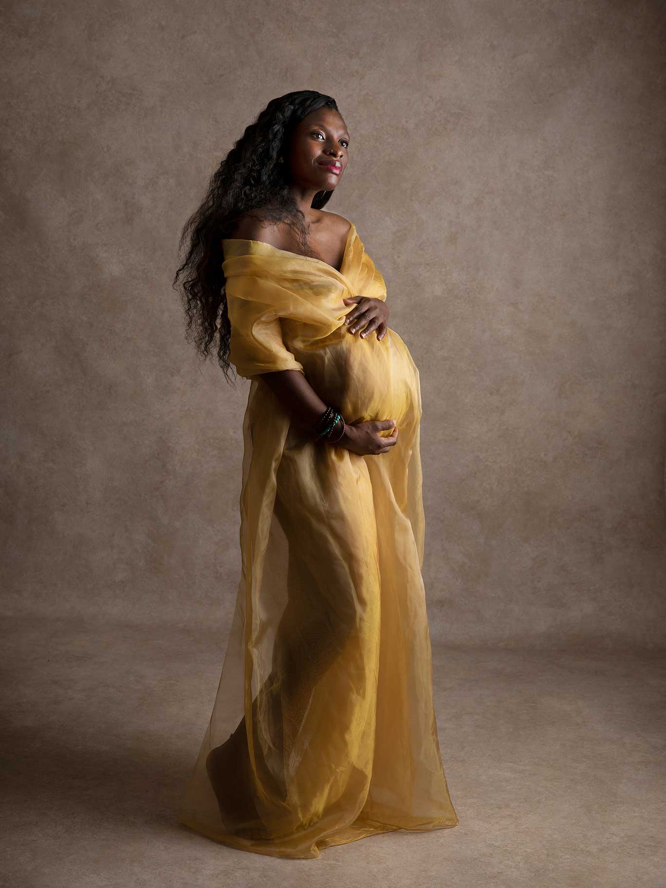 Porträtt som fångar graviditeten på kvinna med vackert gult tug runt sig, taget av Fotograf Anna Arvidsson.