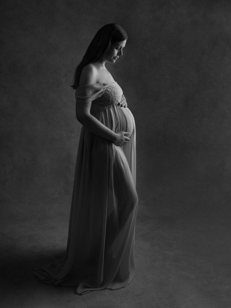 Vacker svartvit bild på en gravid kvinna i vacker, stilren klänning, fångat av fotografen Anna Arvidsson i Malmö.