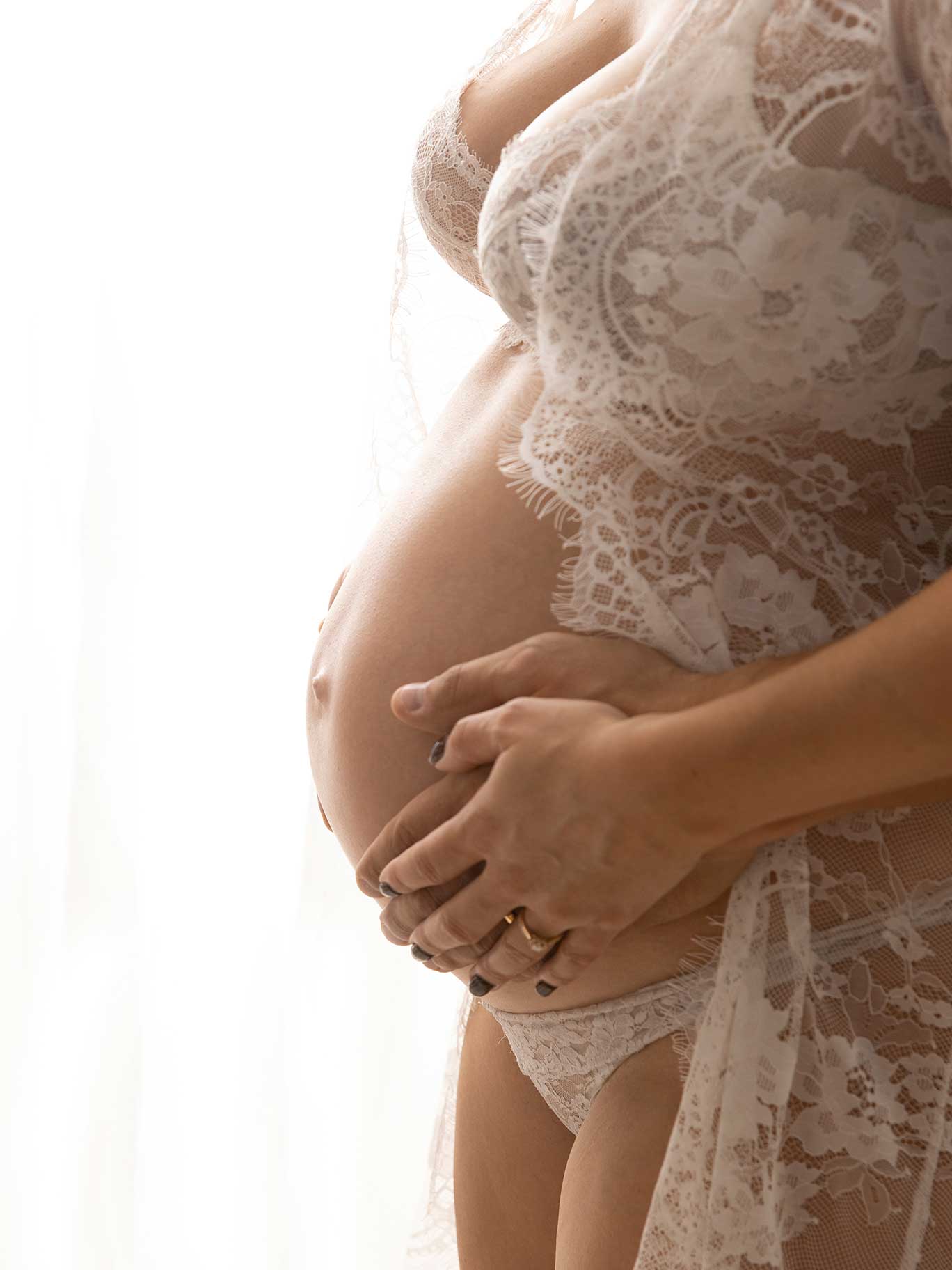 Närbild på en gravidmage i motljus fotograferat i studio i Malmö.