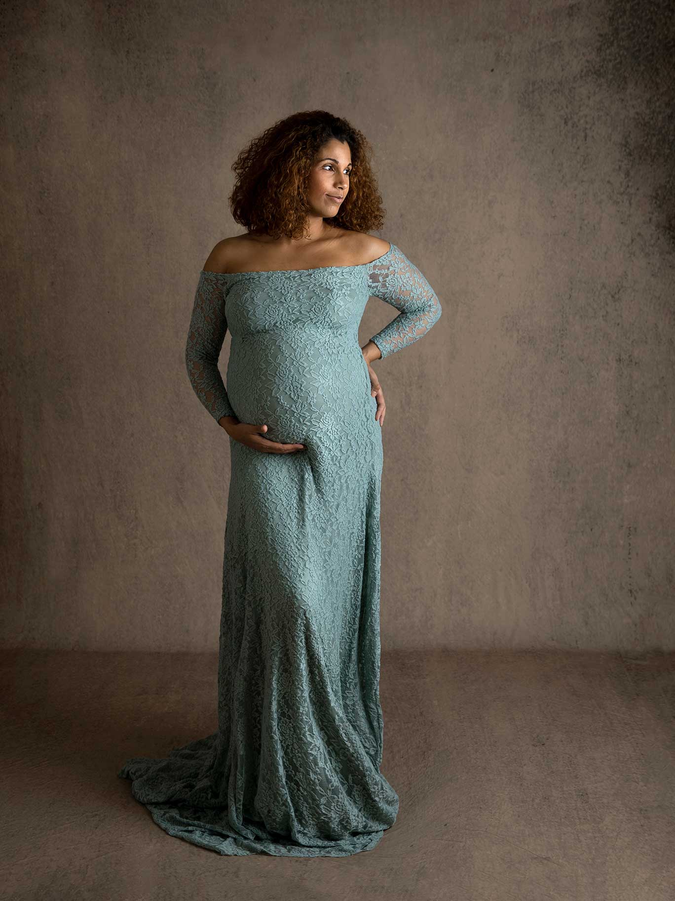 Gravid kvinna ler mjukt under lugn och harmonisk fotografering i studio.