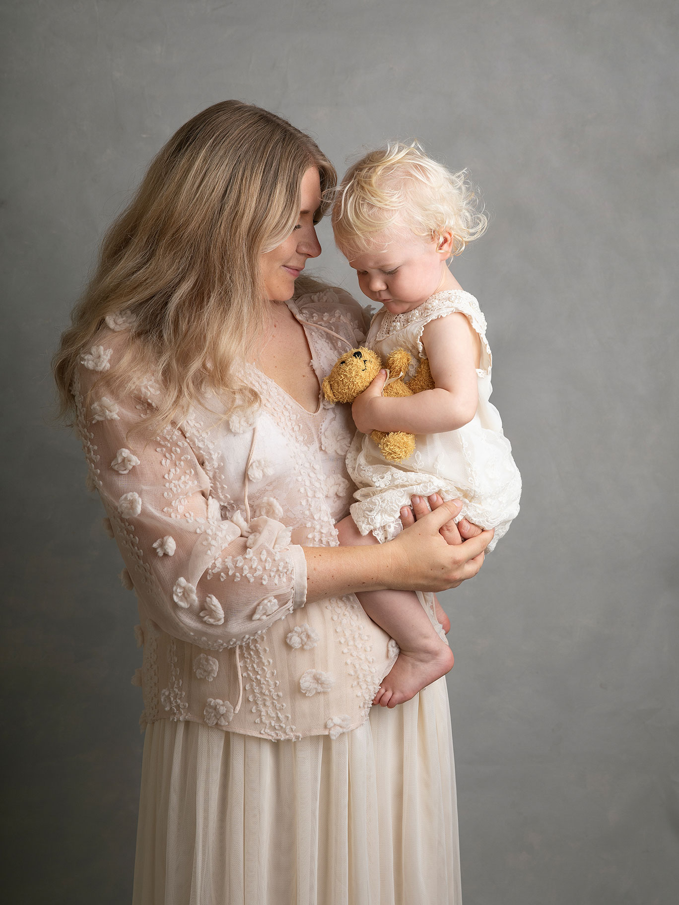 Mamma håller sin lilla flicka i famnen under en fotografering i en fotostudio i Malmö.