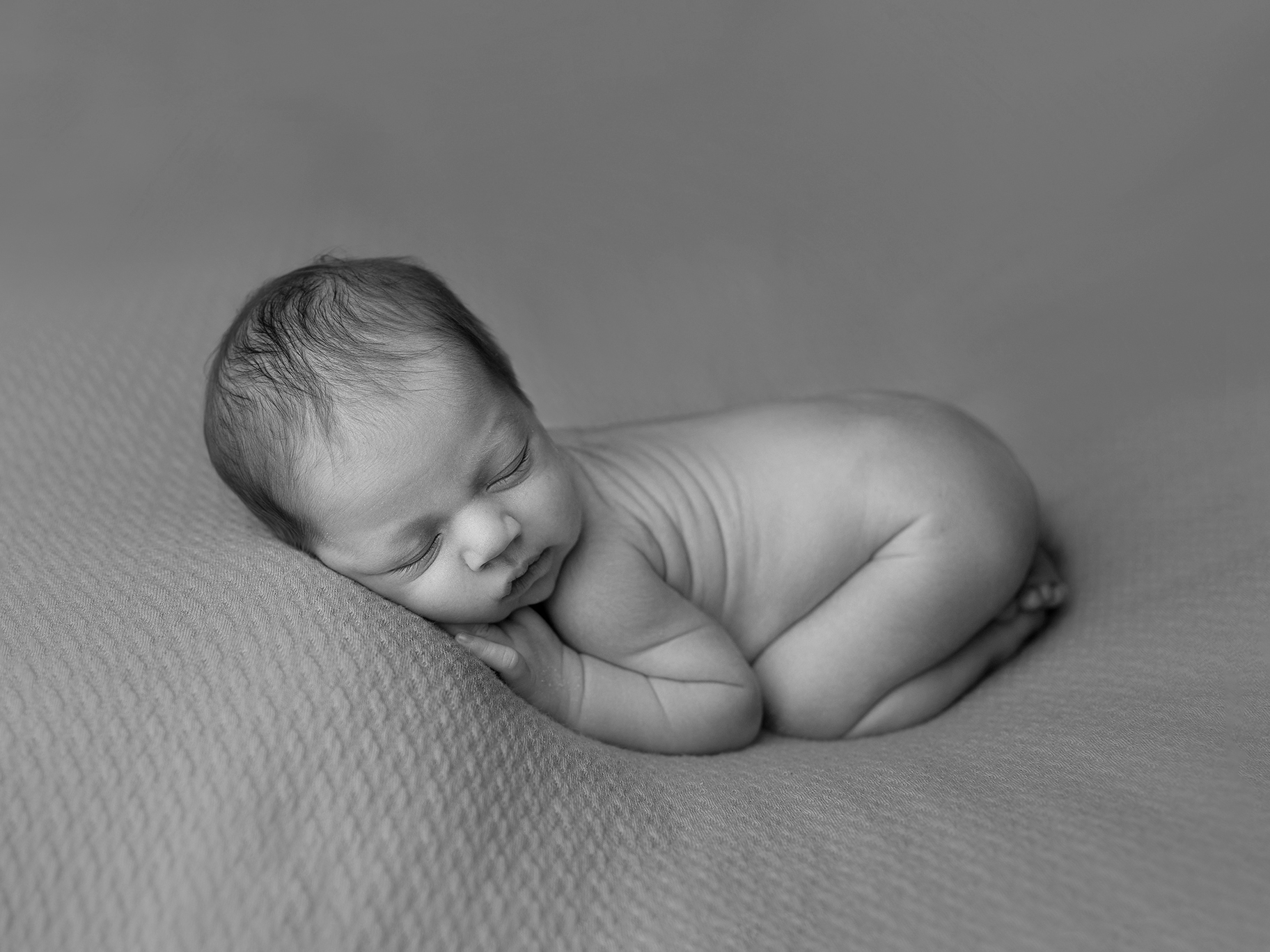 Nyfödd baby på filt fotograferad under sina första dagar i livet i en fotostudio i Skåne.