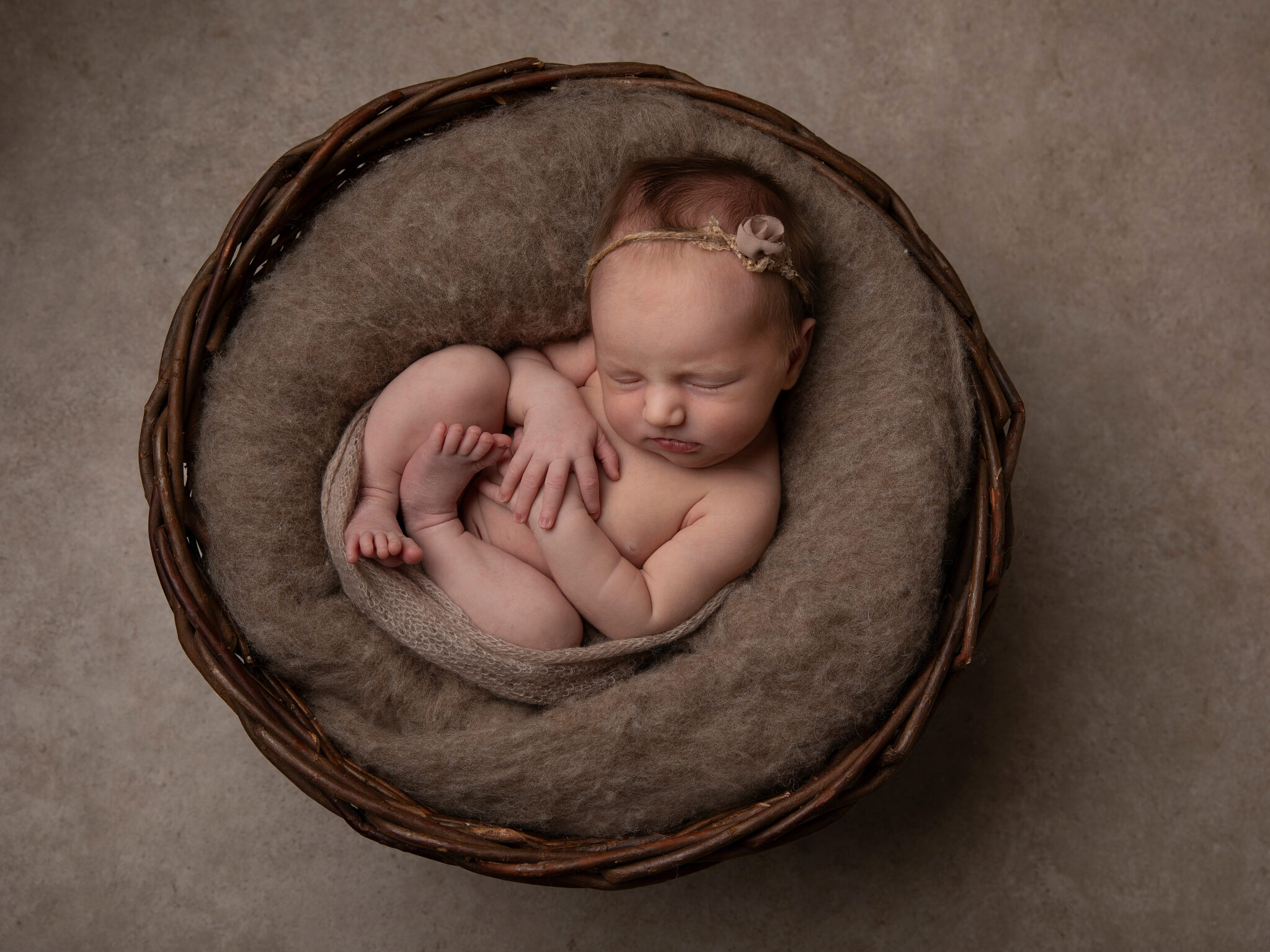 Liten baby i en korg, fotograferad när hon sover under en fotografering i Malmö.