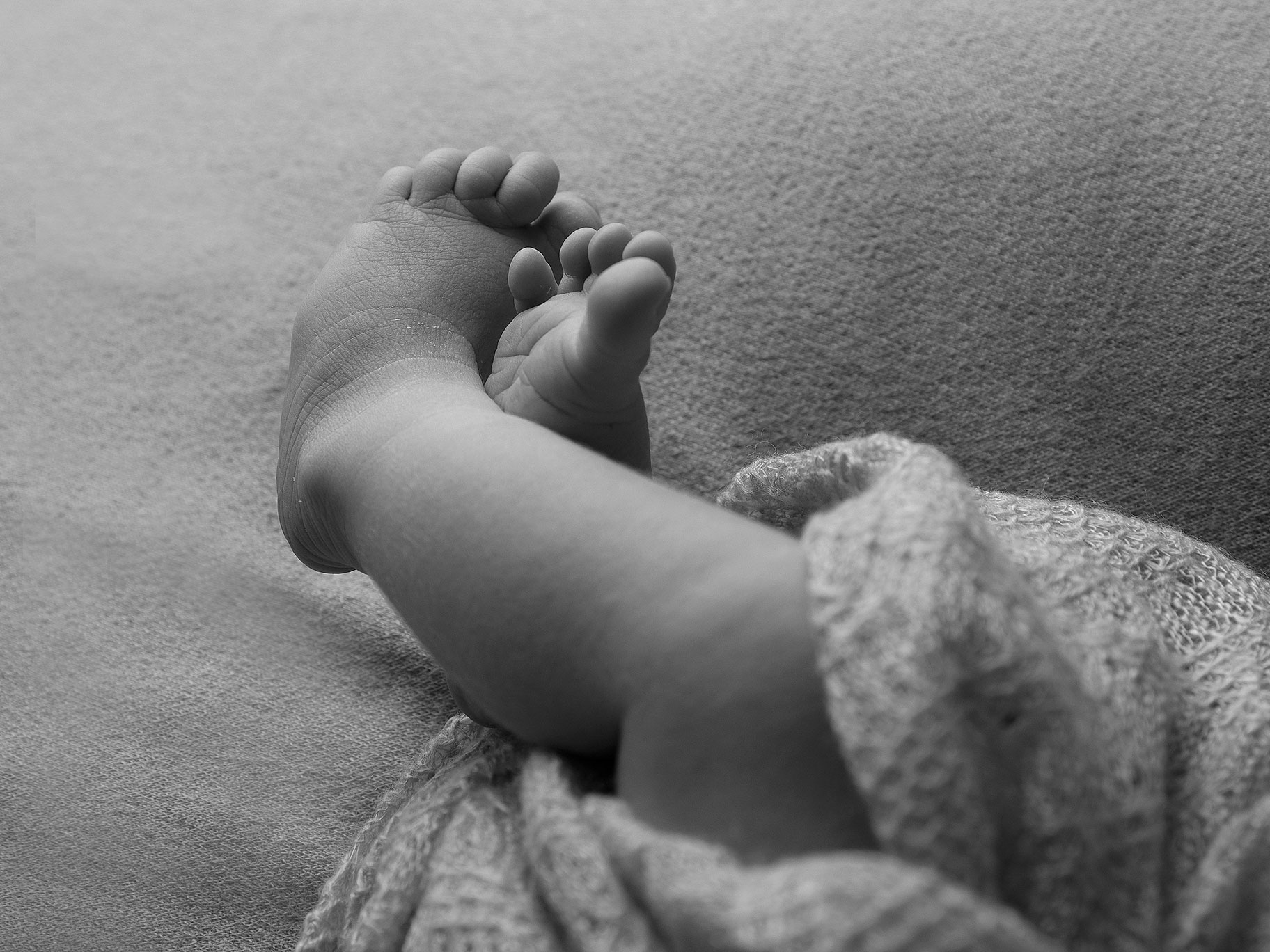 Små babyfötter i fint ljus fotograferat i en studio med blixt.