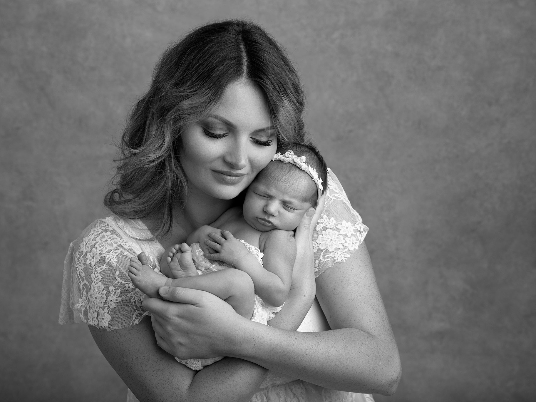 Mamma med sin nyfödda baby i sina händer under en familjefotografering i Malmö.