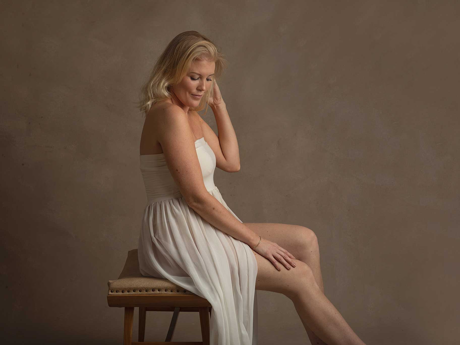 En tjej i vit, skir klänning blir fotograferad när hon tittar ner.