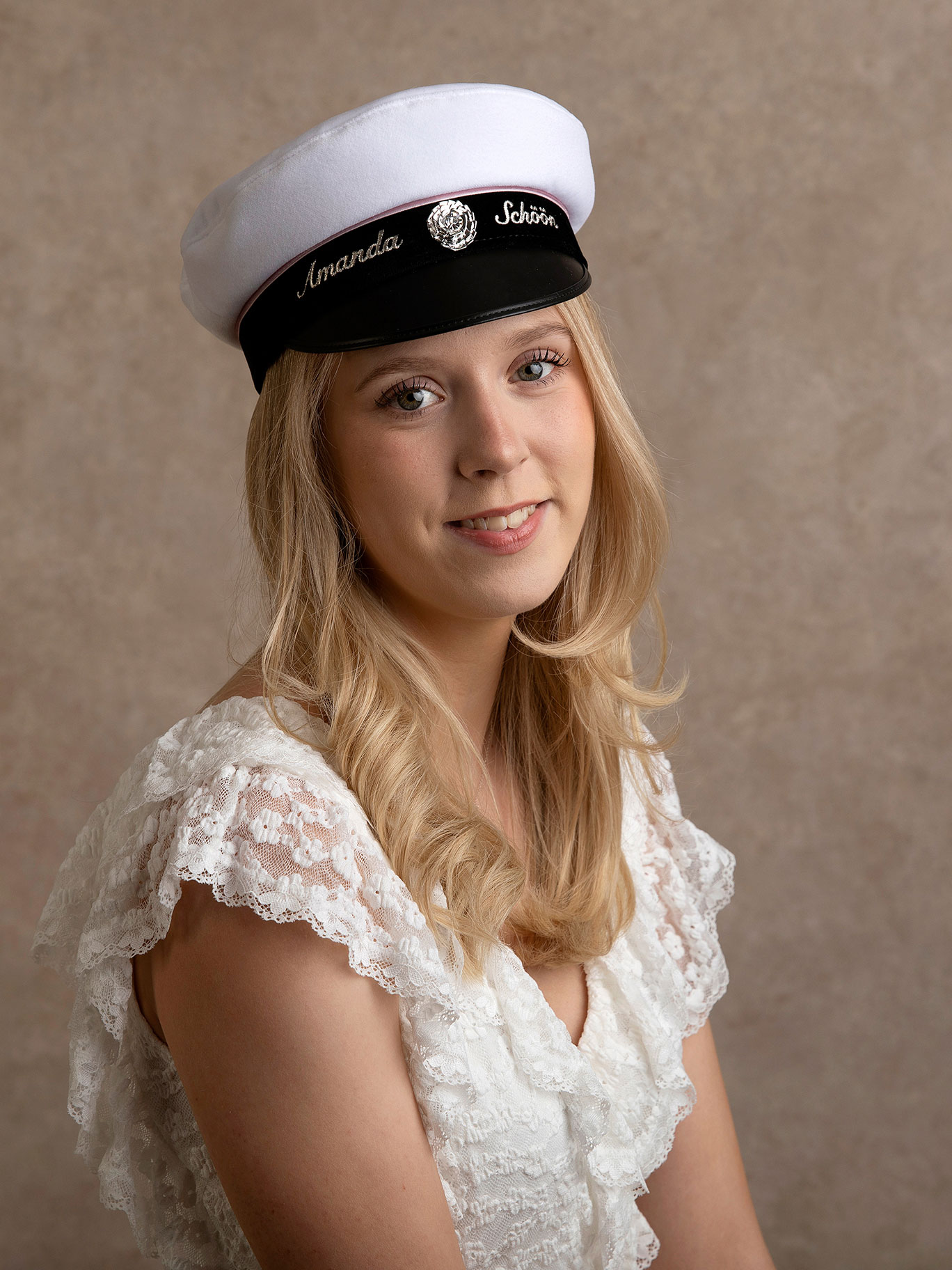 Ung tjej med studentmössa på huvudet blir fotograferad inför sin student i Malmö.