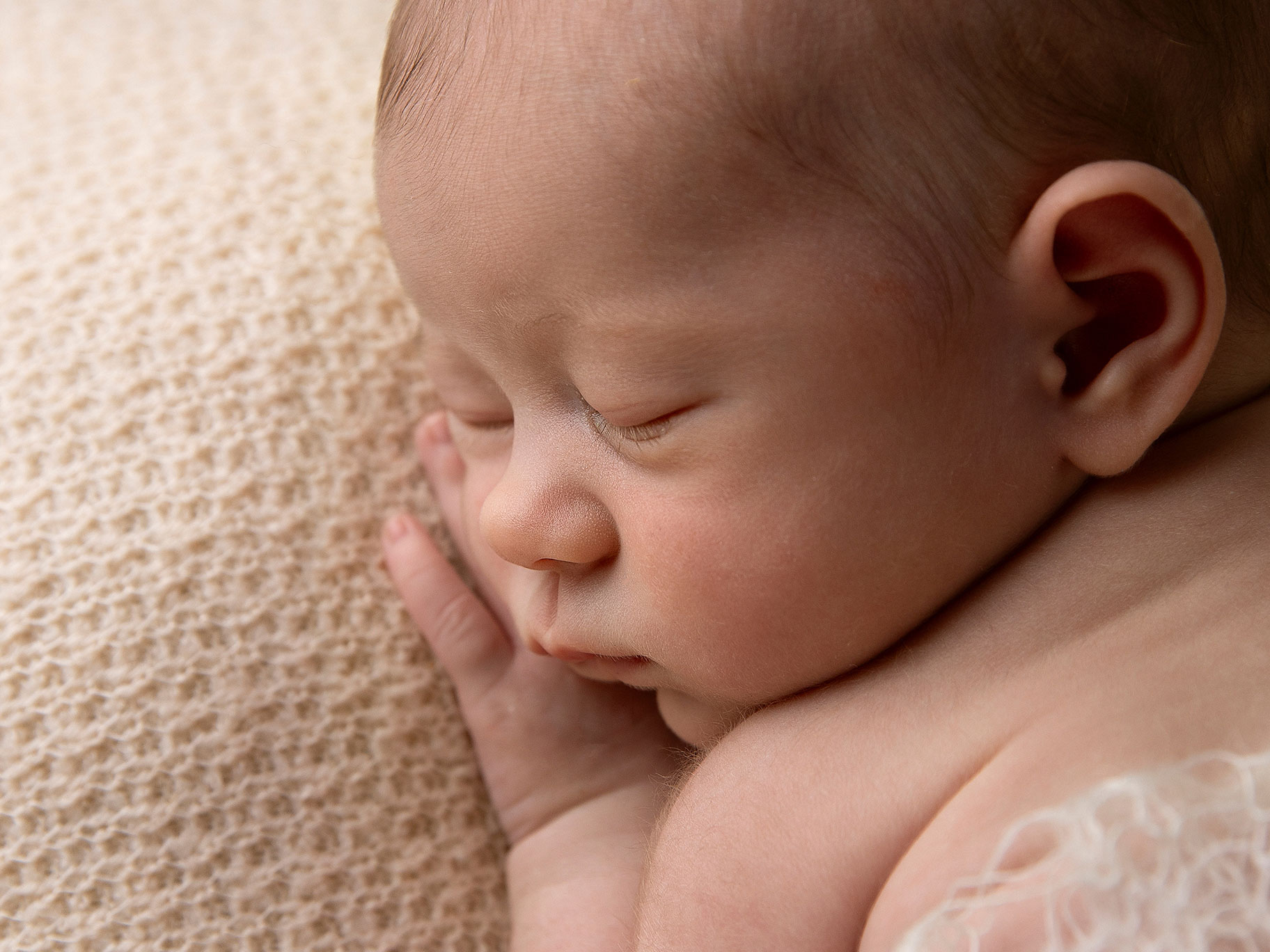 Närbild på en nyfödd liten baby, man ser de fina små ögonfransarna.